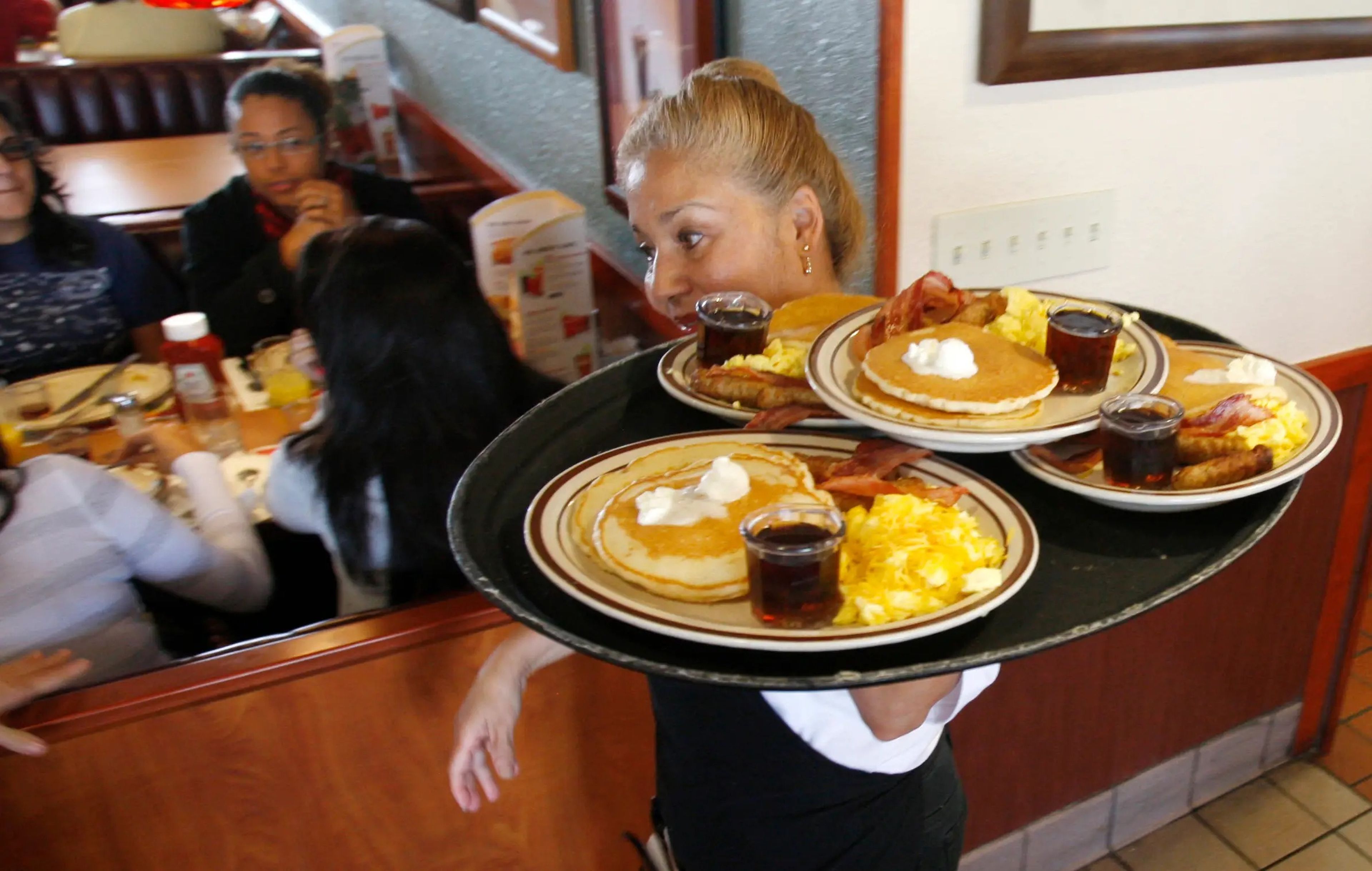 Una camarera de Denny's cargando con una bandeja de desayunos Grand Slam.