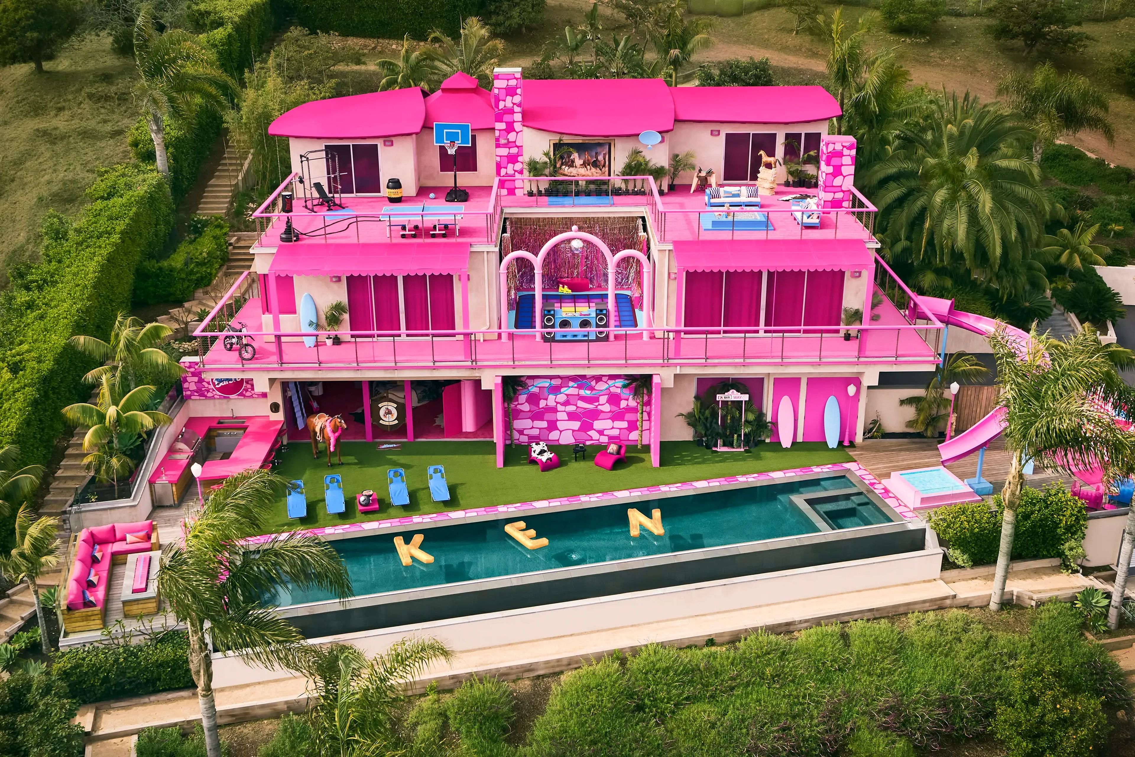 El exterior de la casa rosa de Barbie en Malibú. Los flotadores de la piscina están dispuestos de manera que deletrean "KEN" en el agua.