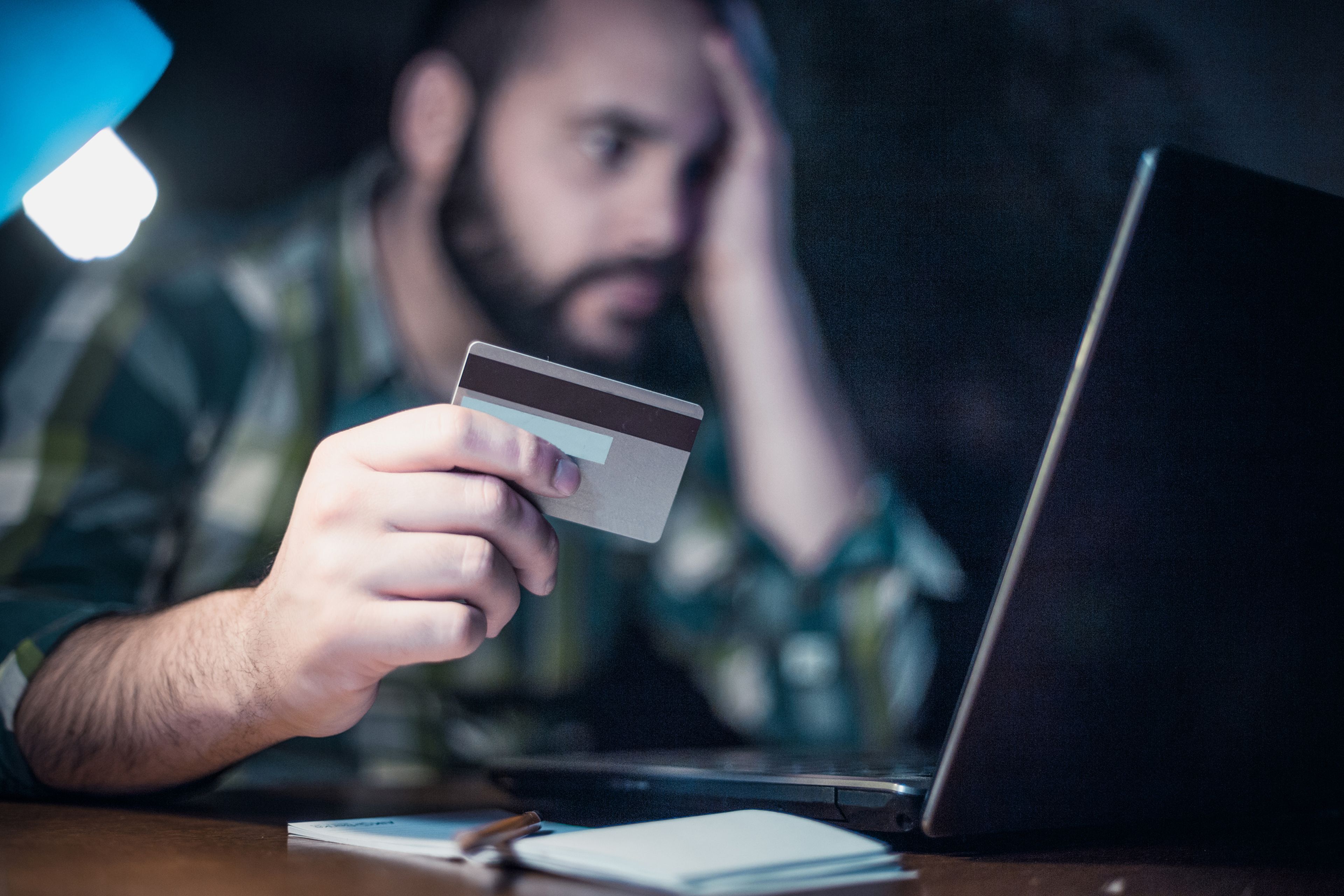 Hombre preocupado con tarjeta de crédito y ordenador