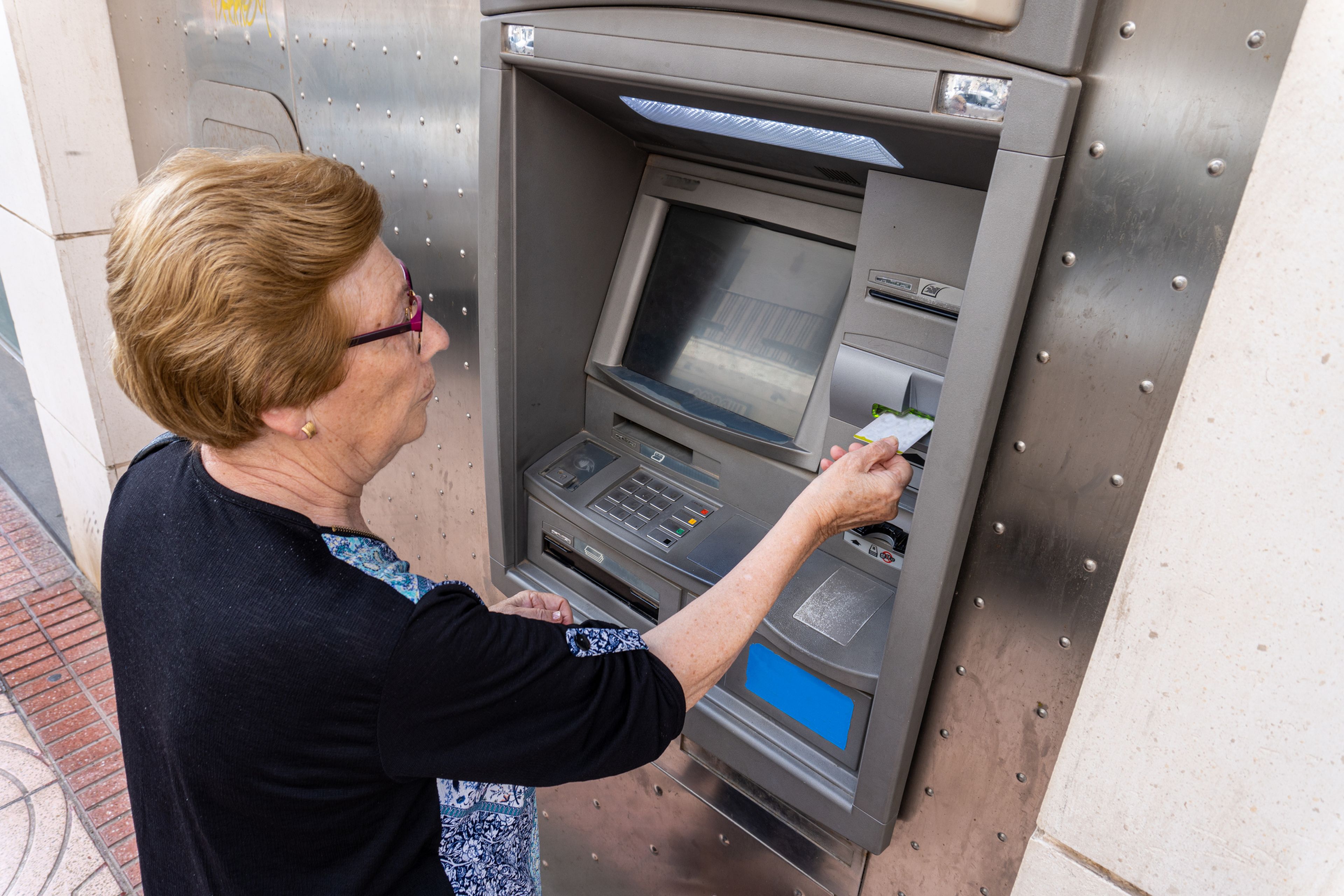 Mujer mayor saca dinero de cajero automático