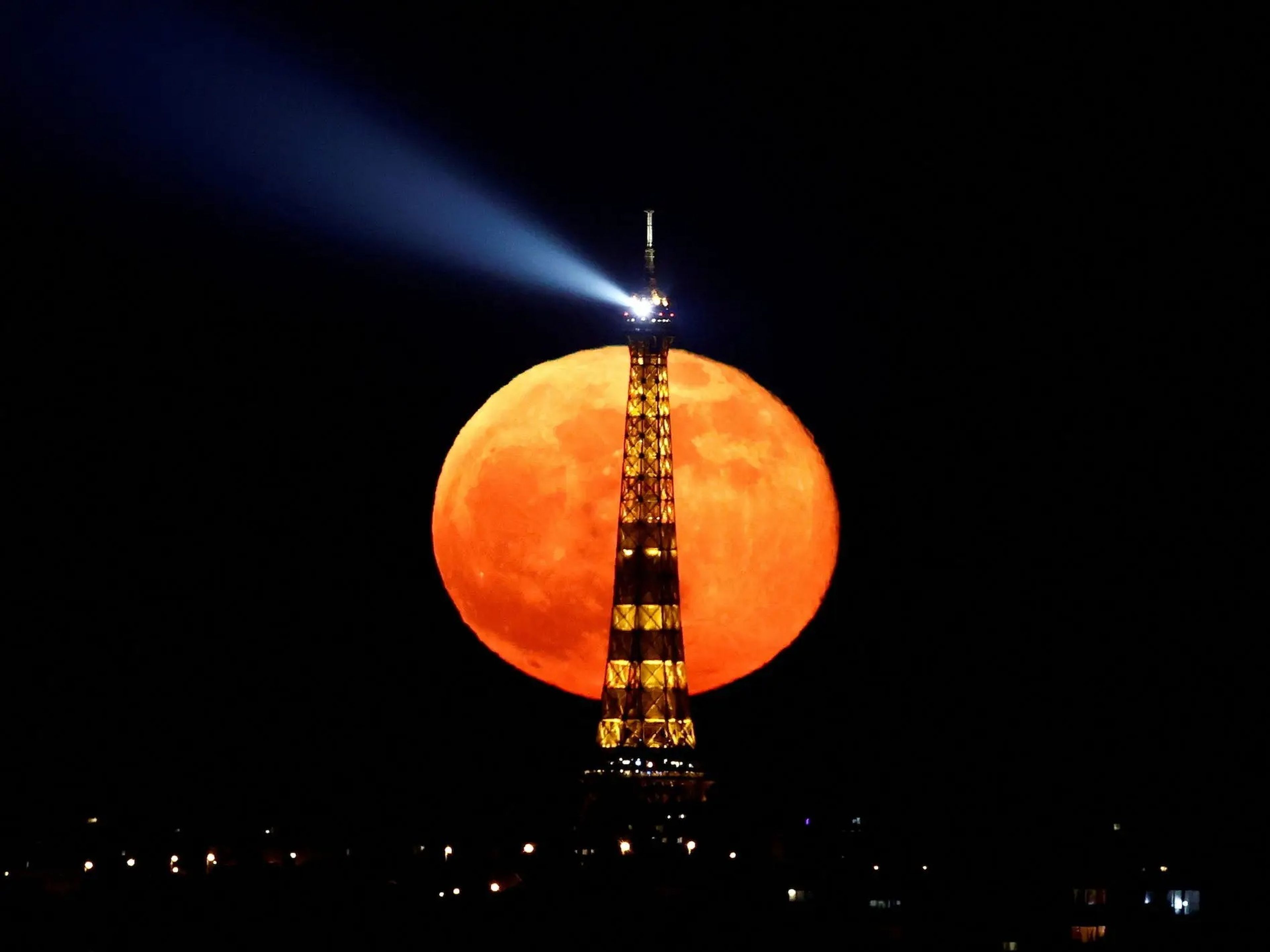 La luna llena se eleva detrás de la Torre Eiffel en París, Francia.