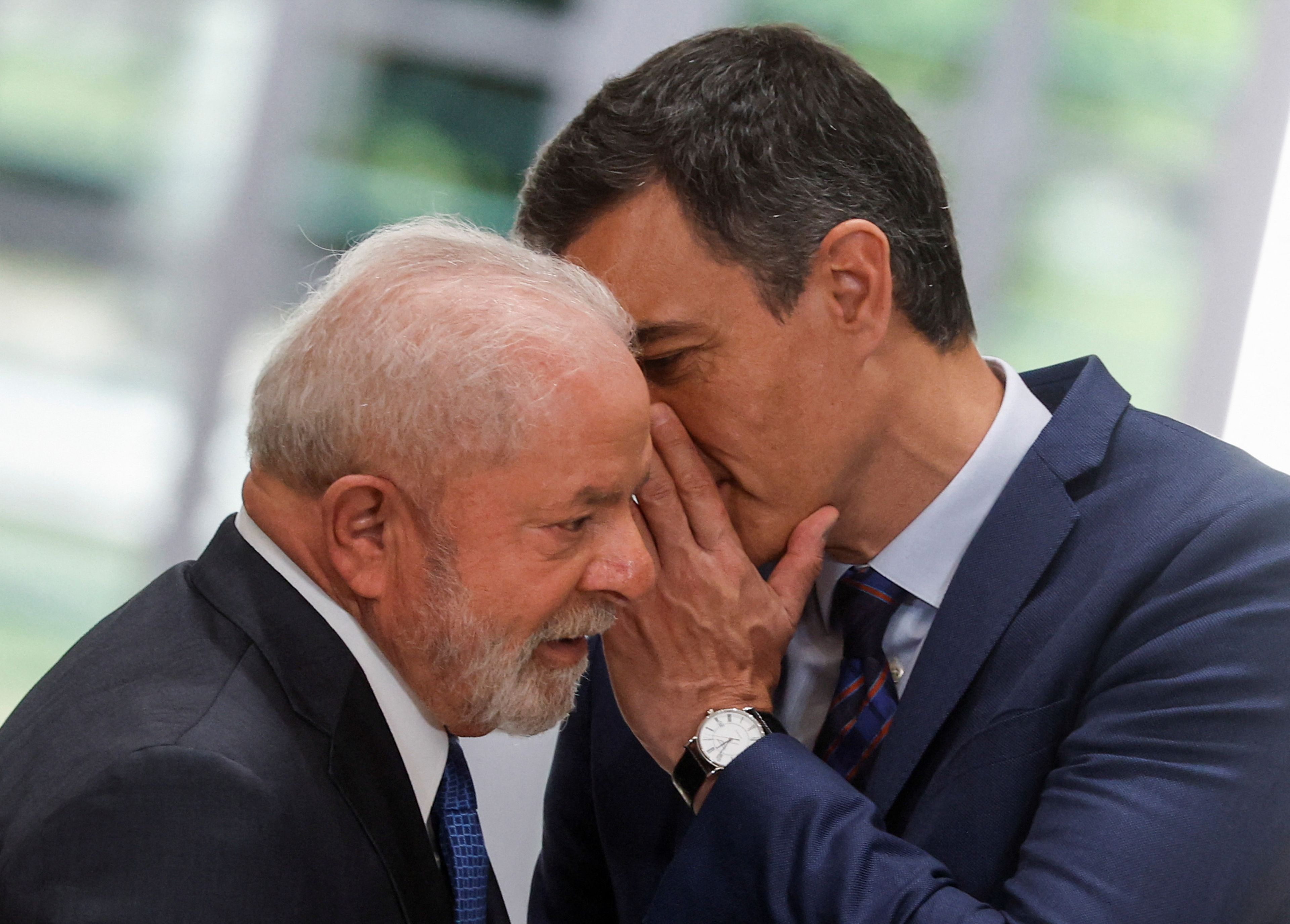 Pedro Sánchez diciéndole algo al oído a Lula da Silva, presidente de Brasil.