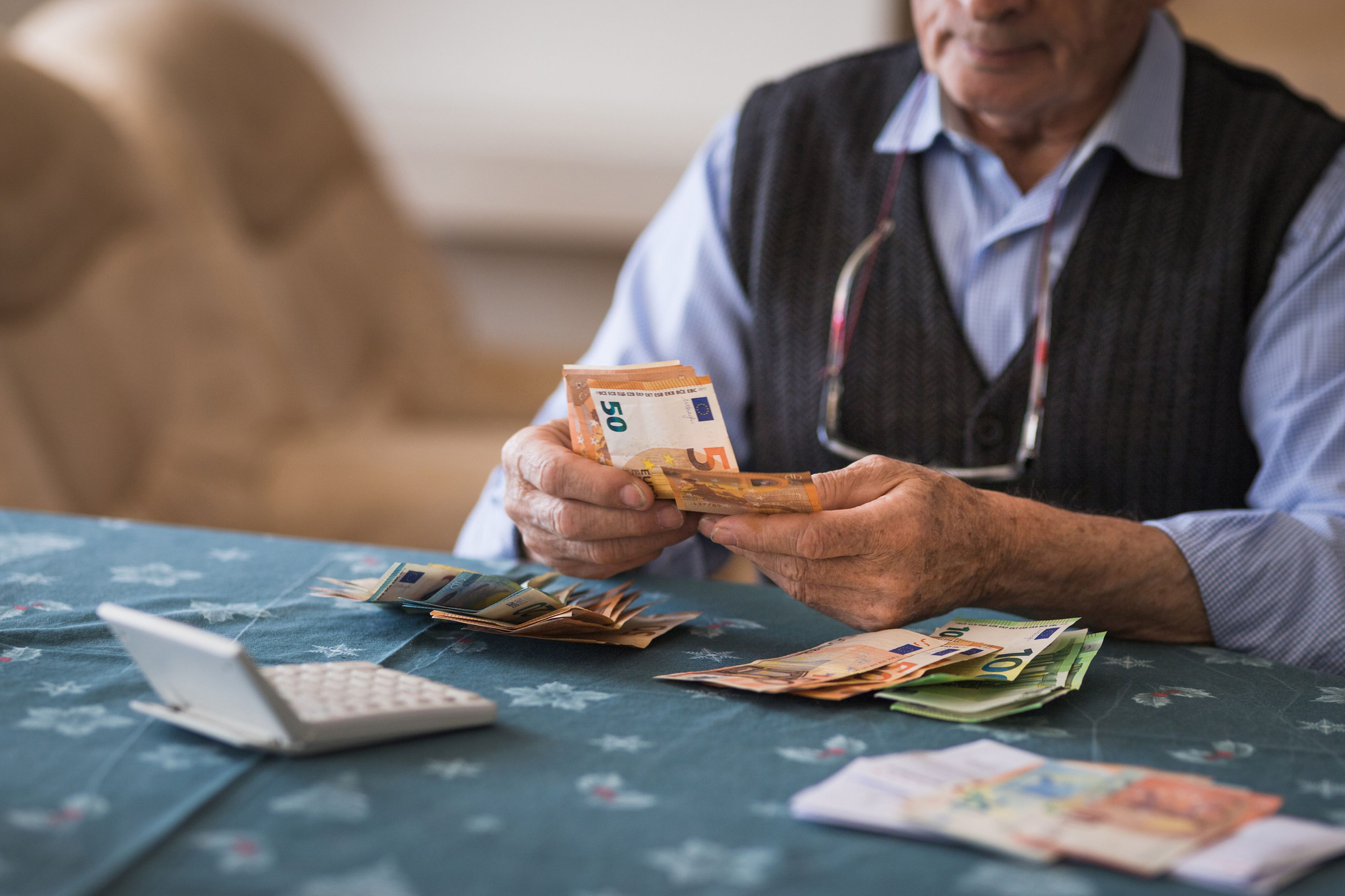 Pensionista, anciano cuenta dinero con calculadora