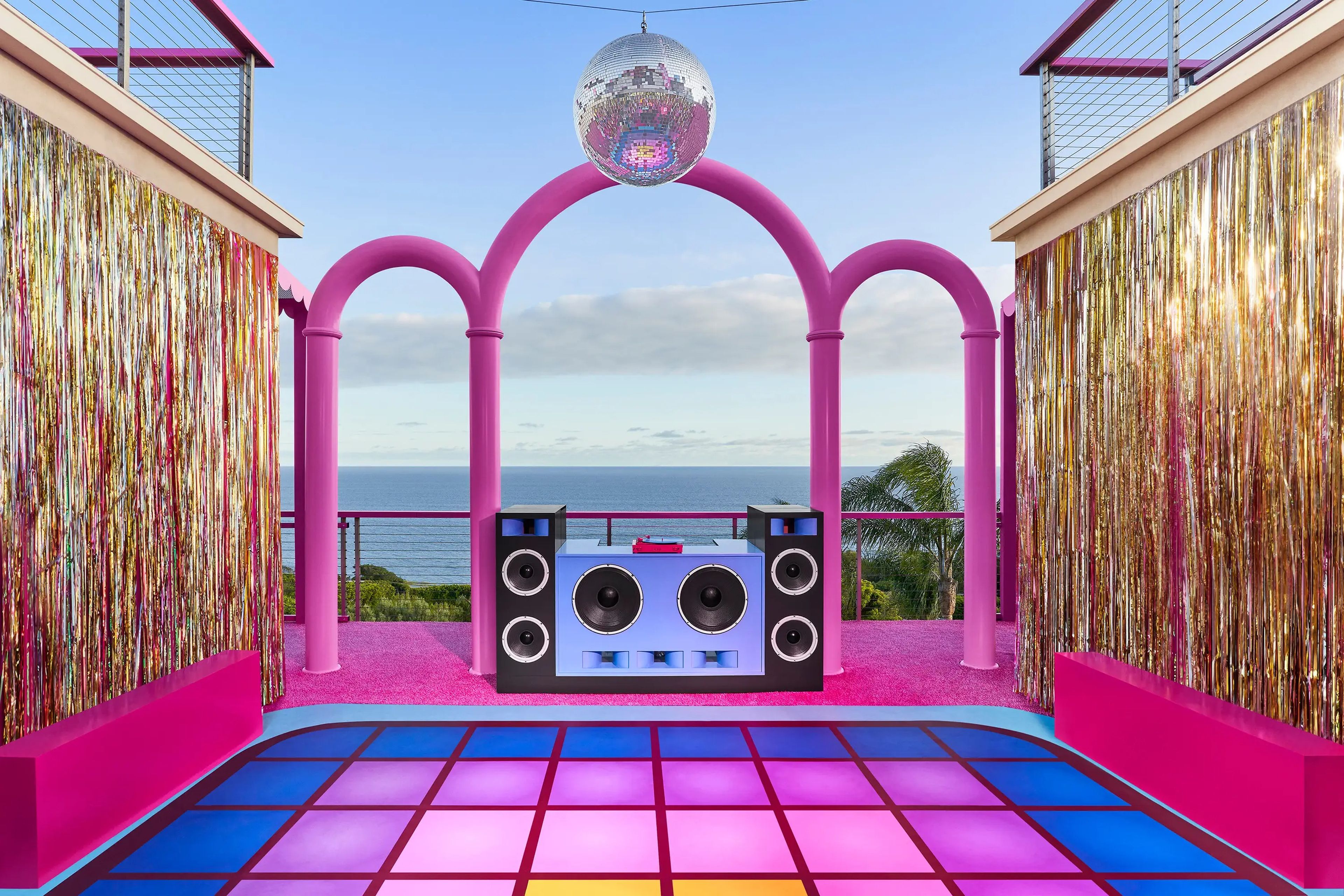 There is an outdoor space that's been transformed into a disco roller rink with neon, tiled floors and a DJ speaker set.