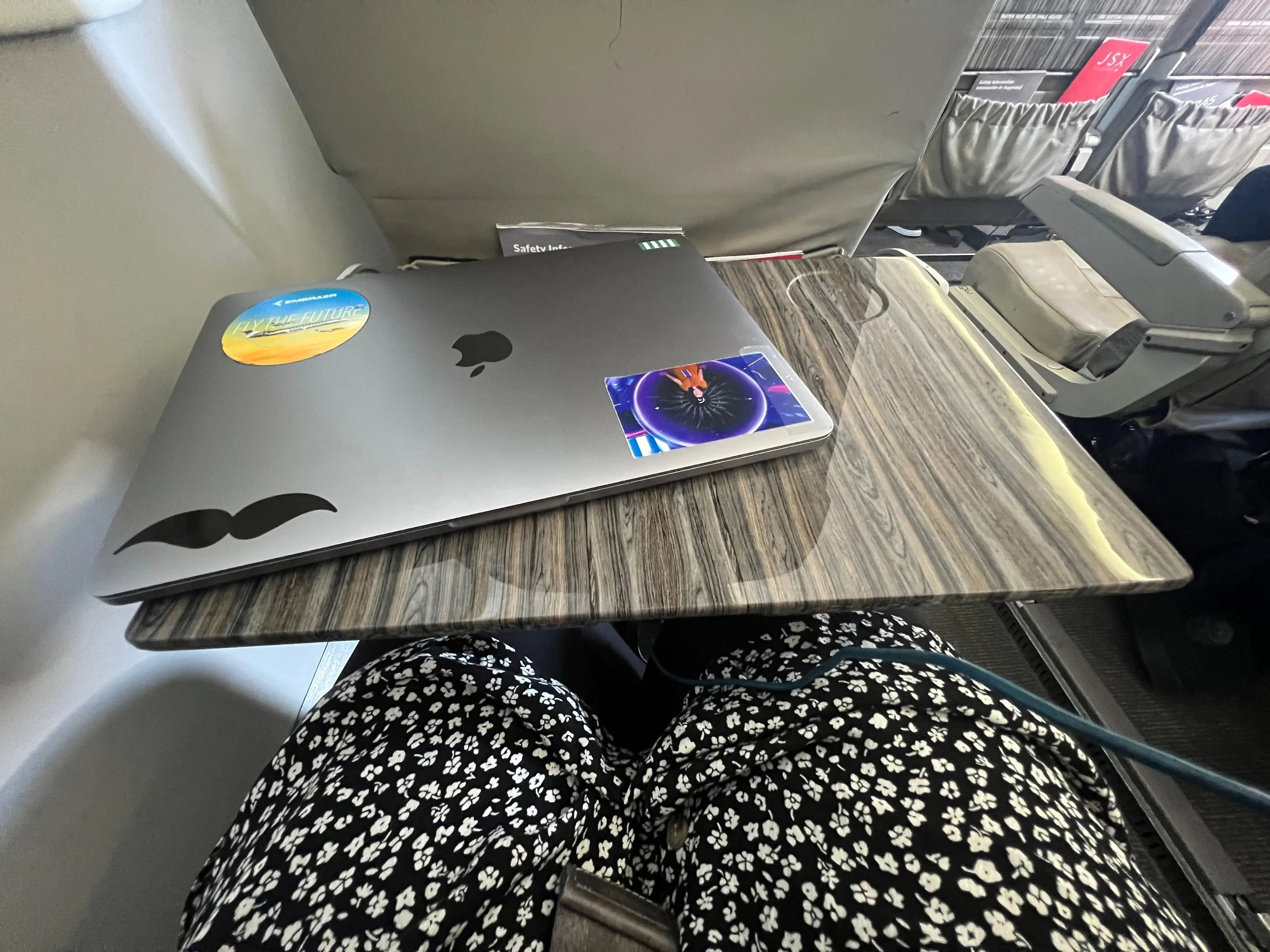 The author's laptop placed on the top of the tray table which still has room to hold a drink.
