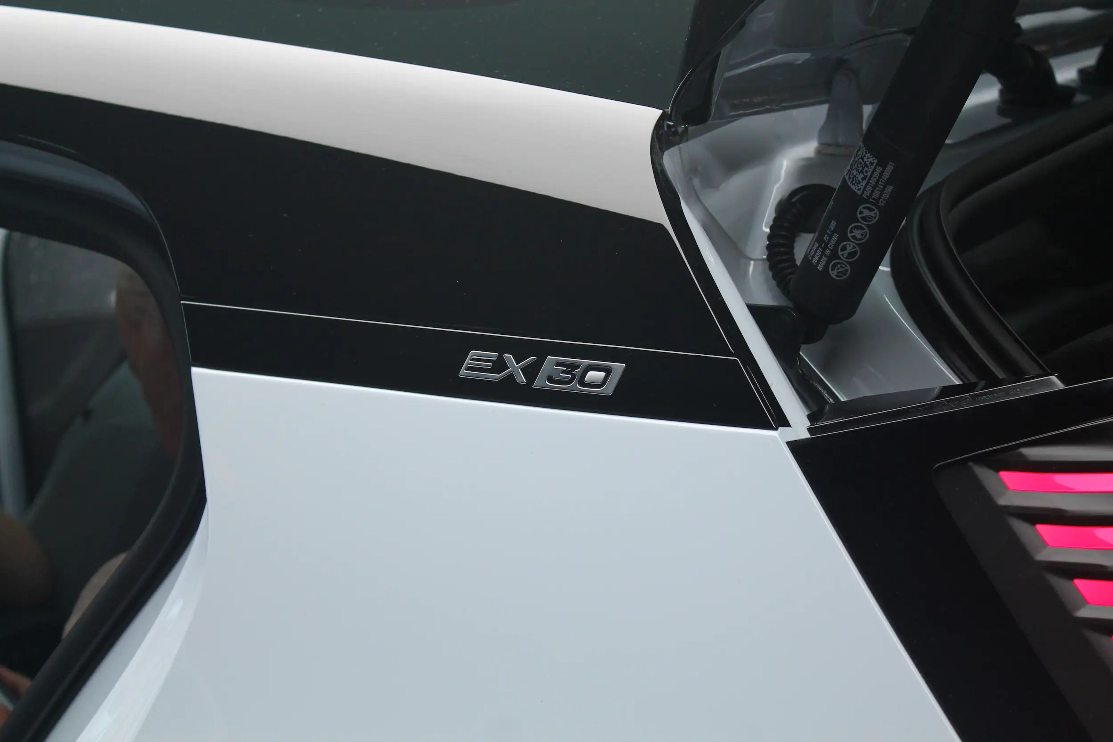 La parte trasera izquierda del Volvo EX30, que tiene el maletero abierto y "EX30" escrito en el lateral con letras de aspecto elegante.