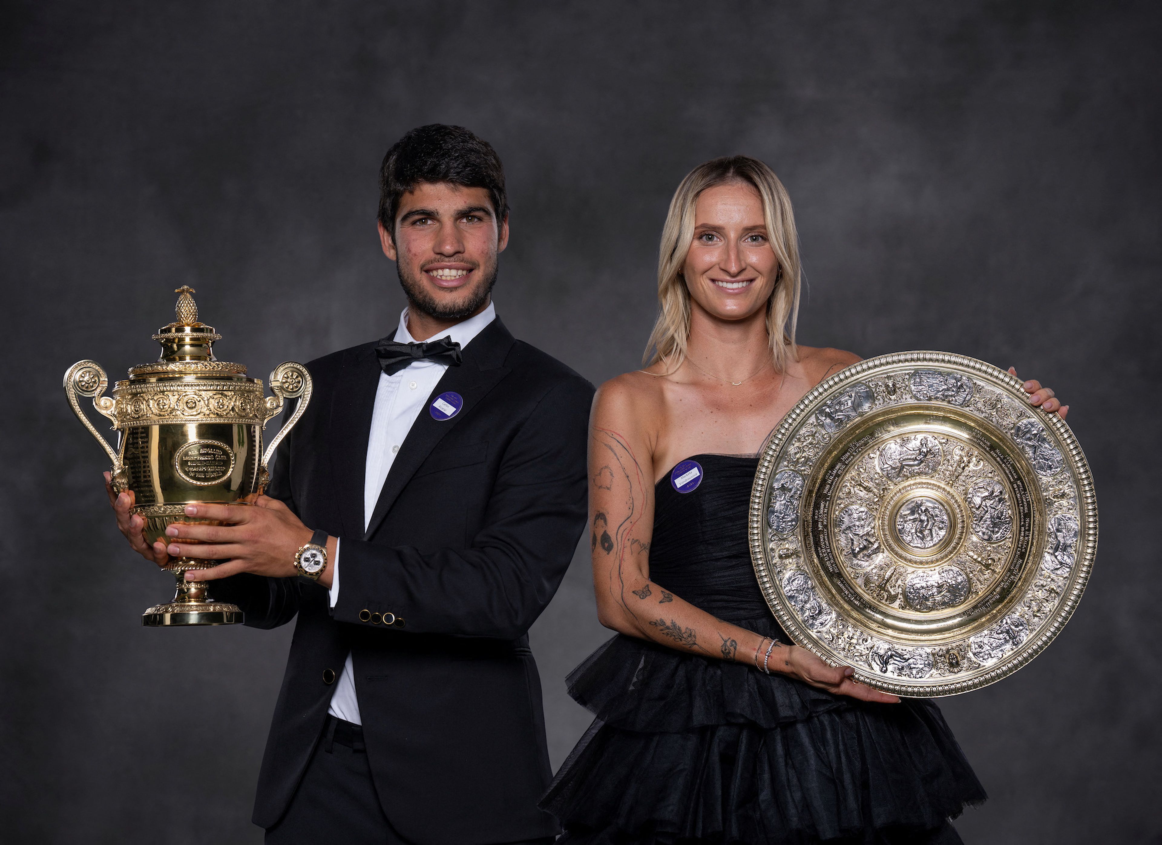 Carlos Alcaraz y Marketa Vondrousova, campeones de Wimbledon 2023, posan con los trofeos en la cena de campeones al final del torneo.