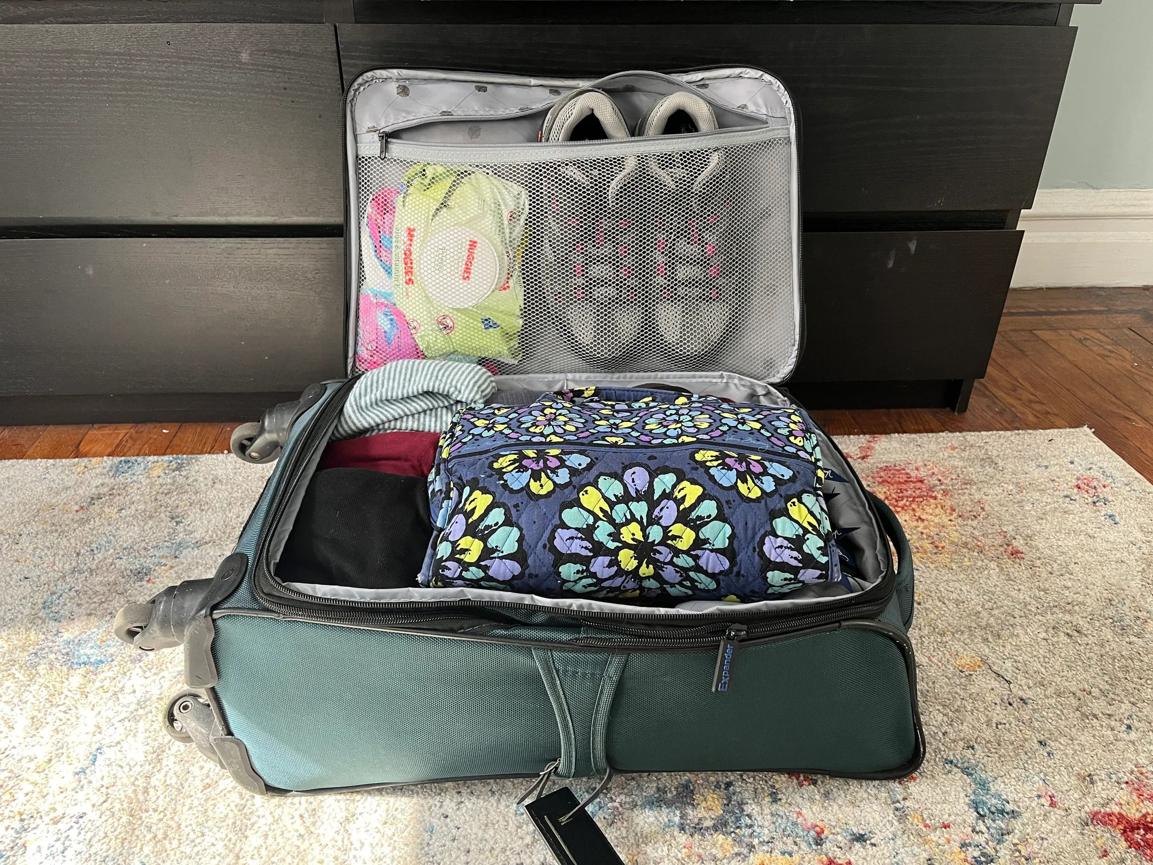 A carry on suitcase packed with shoes and clothes