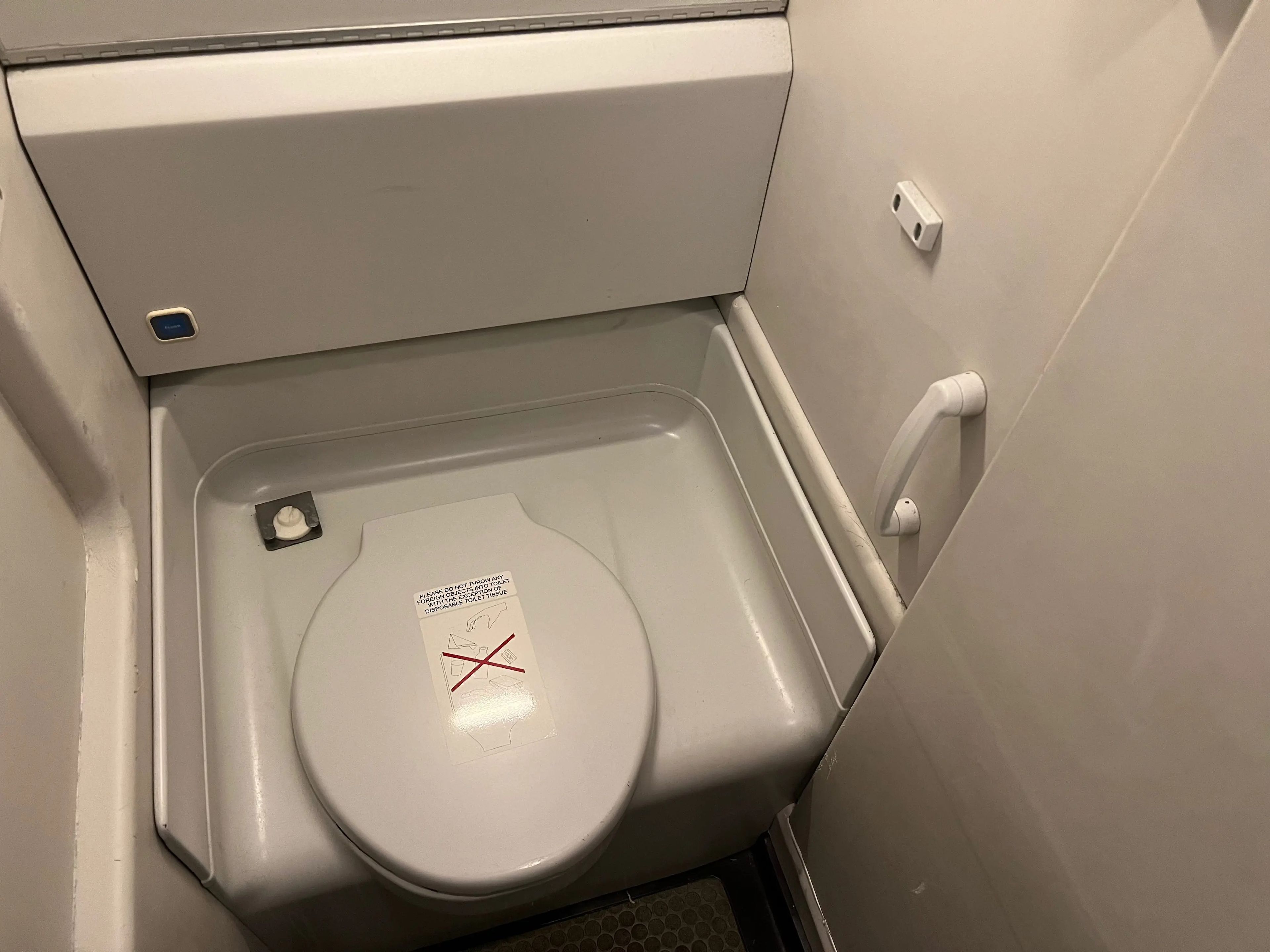 A grey toilet installed in the bathroom facilities on the plane.