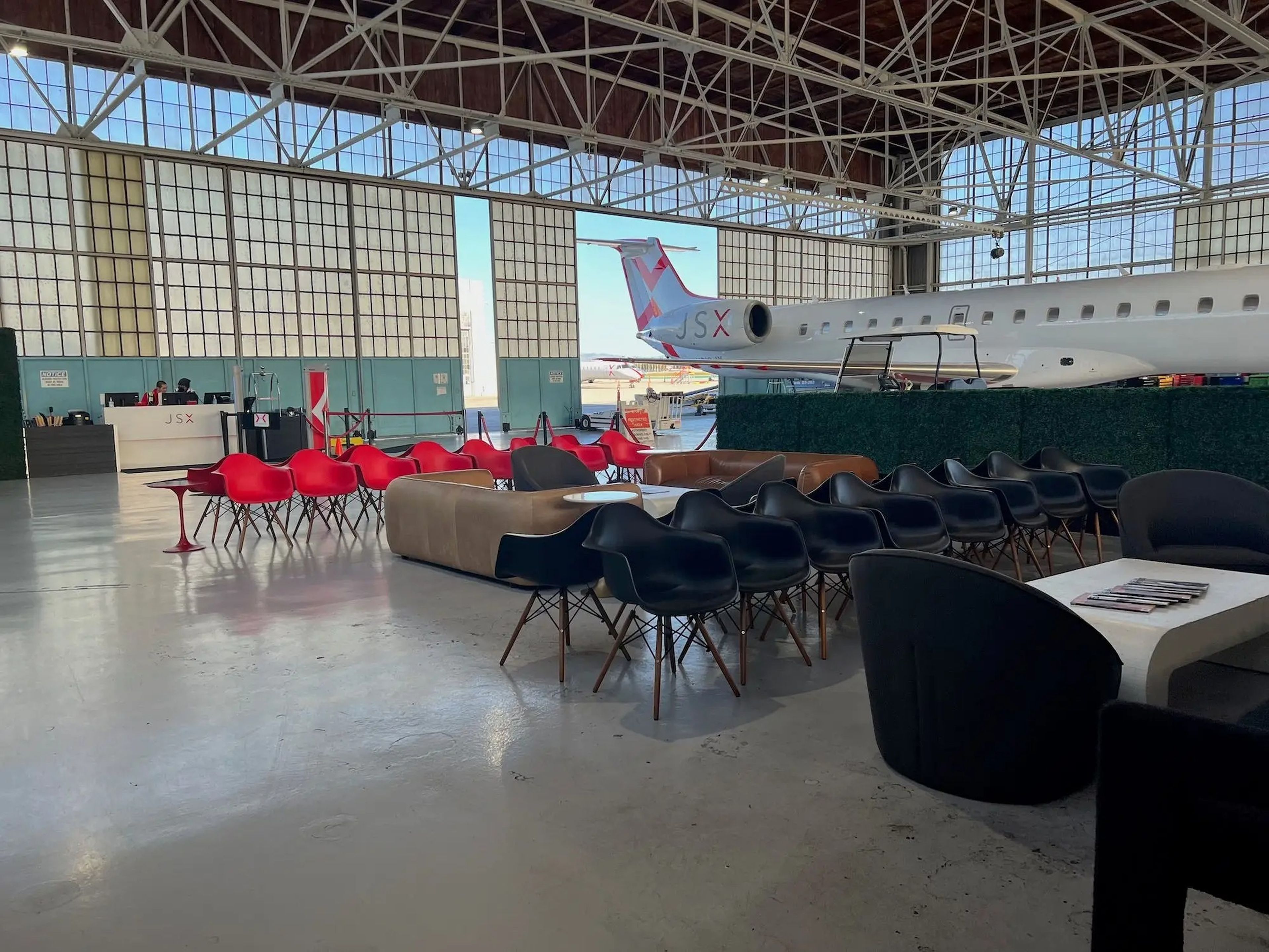 A hangar full of chairs and a white JSX branded aircraft.