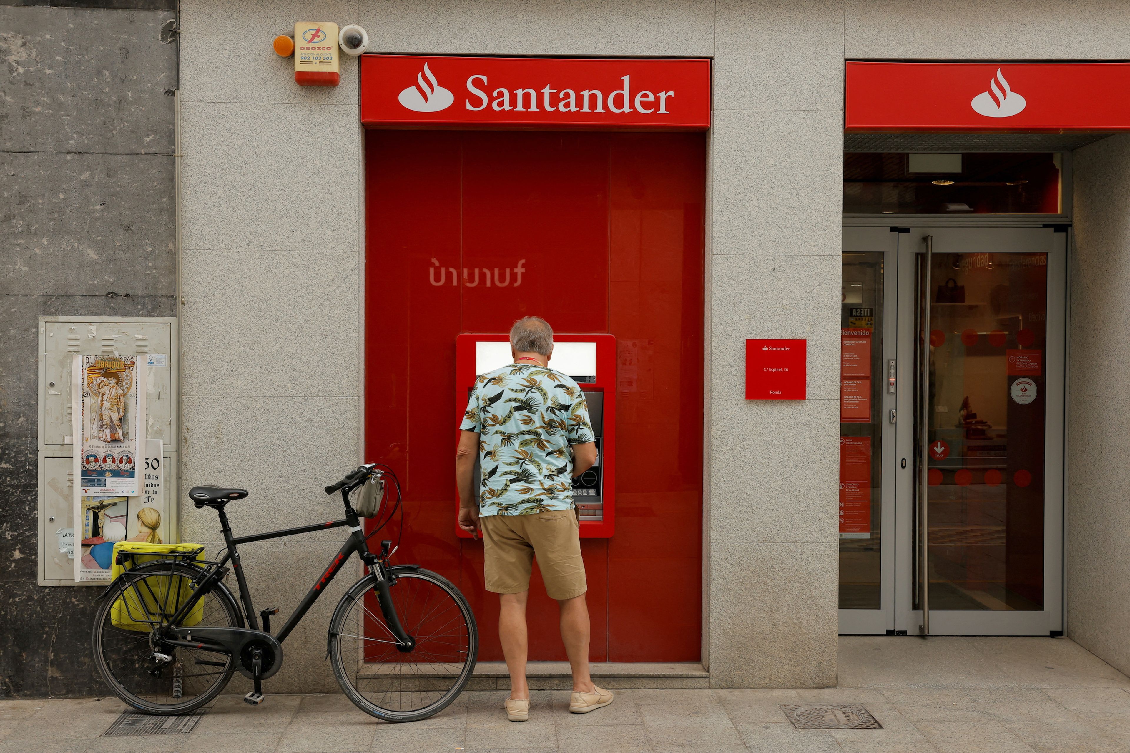 Un hombre saca dinero en un cajero del banco Santander.