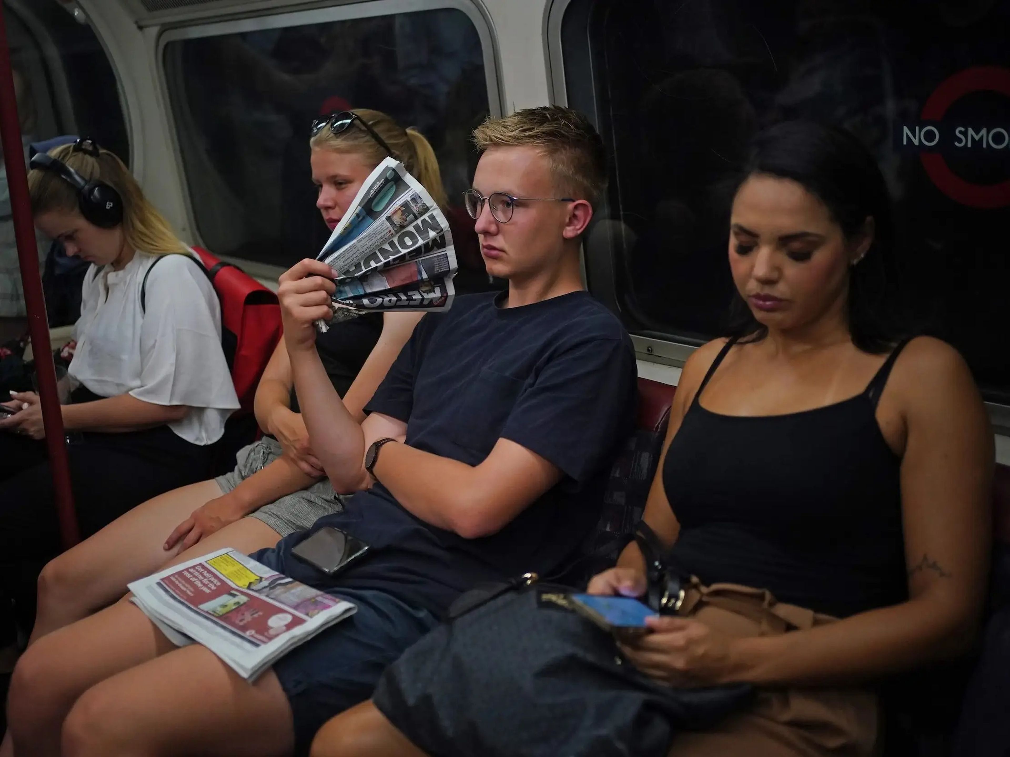 Un hombre utilizando un periódico como abanico en el metro de Londres durante una ola de calor.