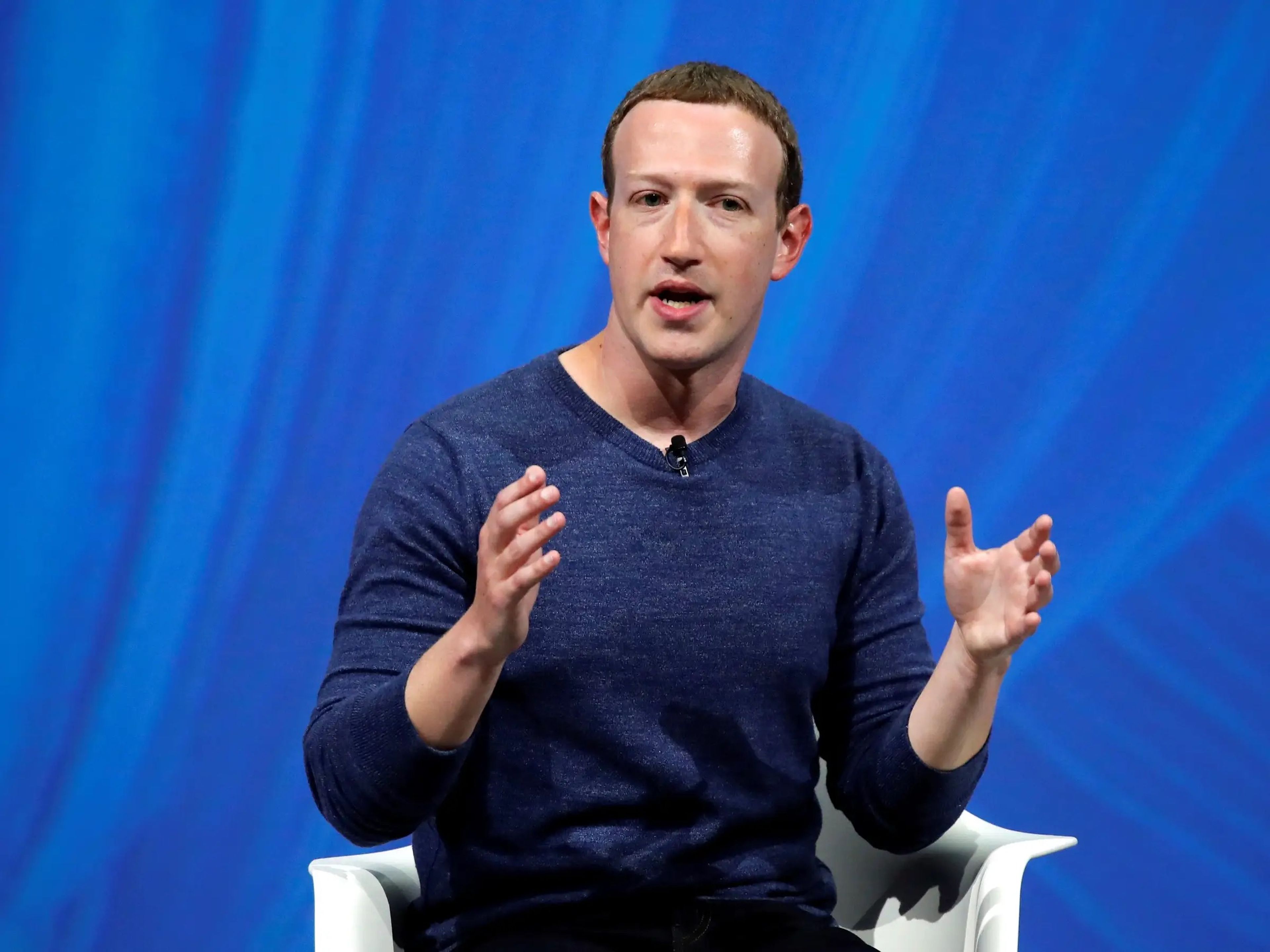 Mark Zuckerberg speaks on stage against a blue background.