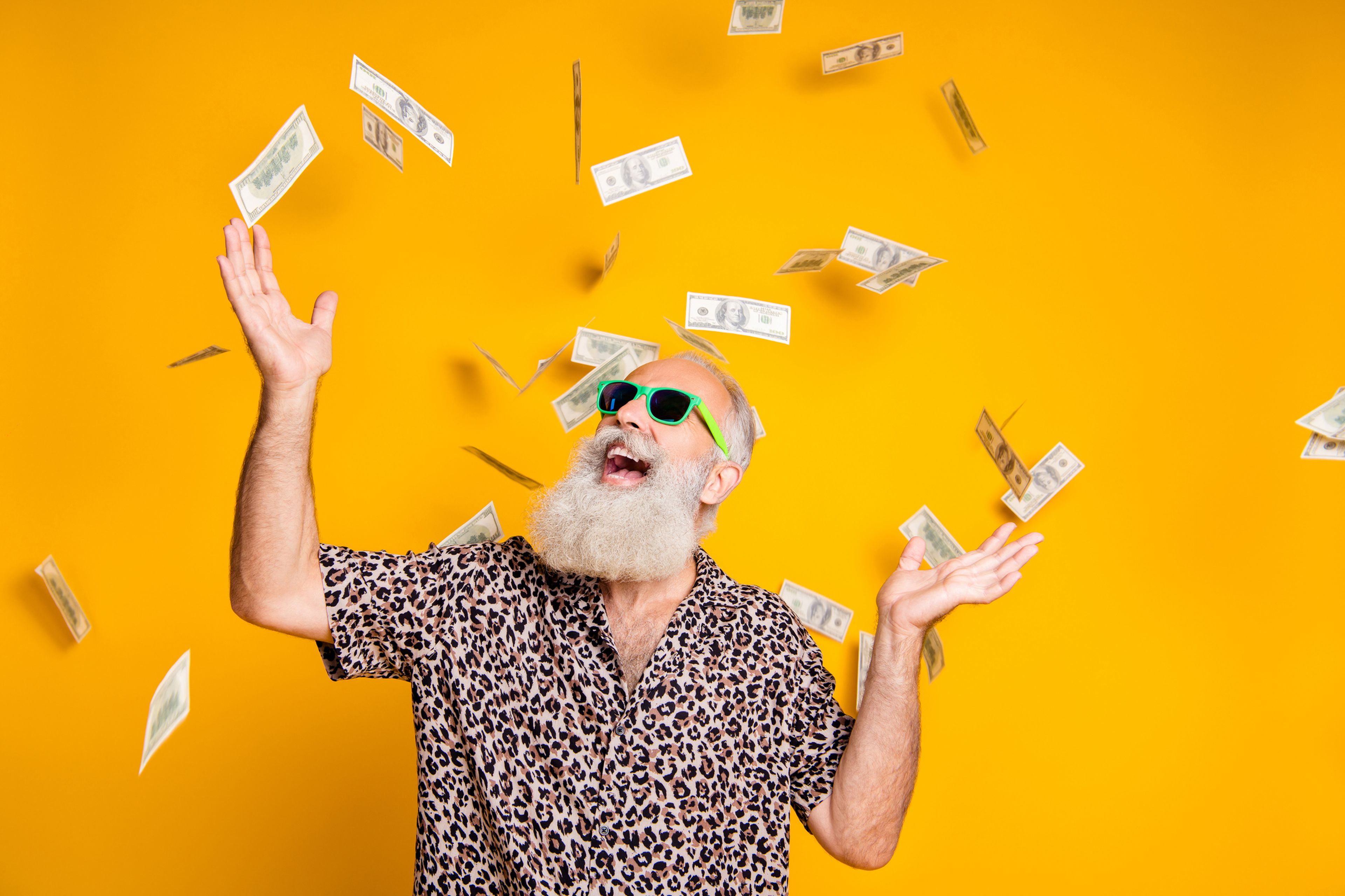 Una persona con gafas de sol y barba con muchos billetes de dólares volando a su alrededor.