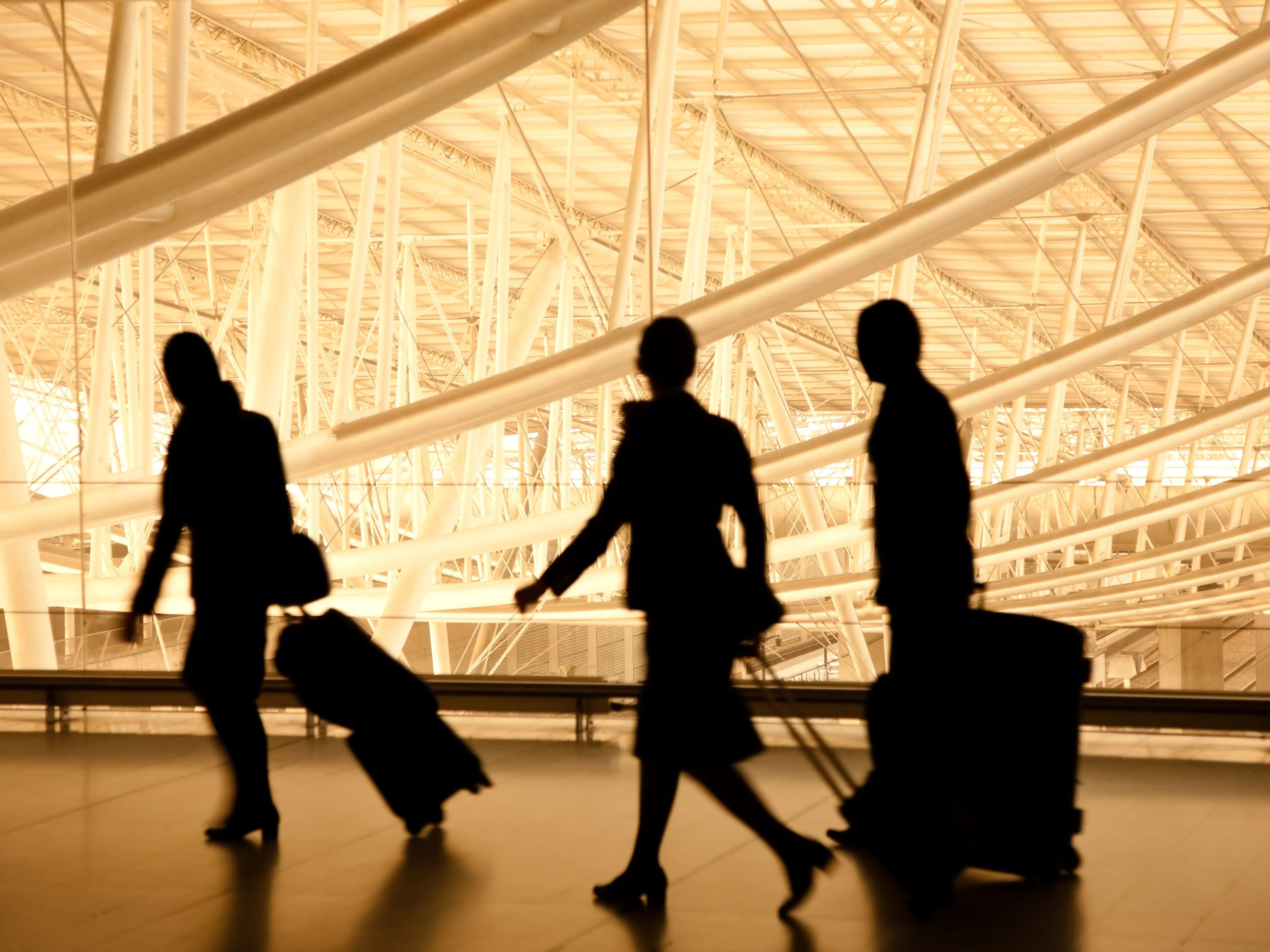 silhouette of three travelers in airport with luggage