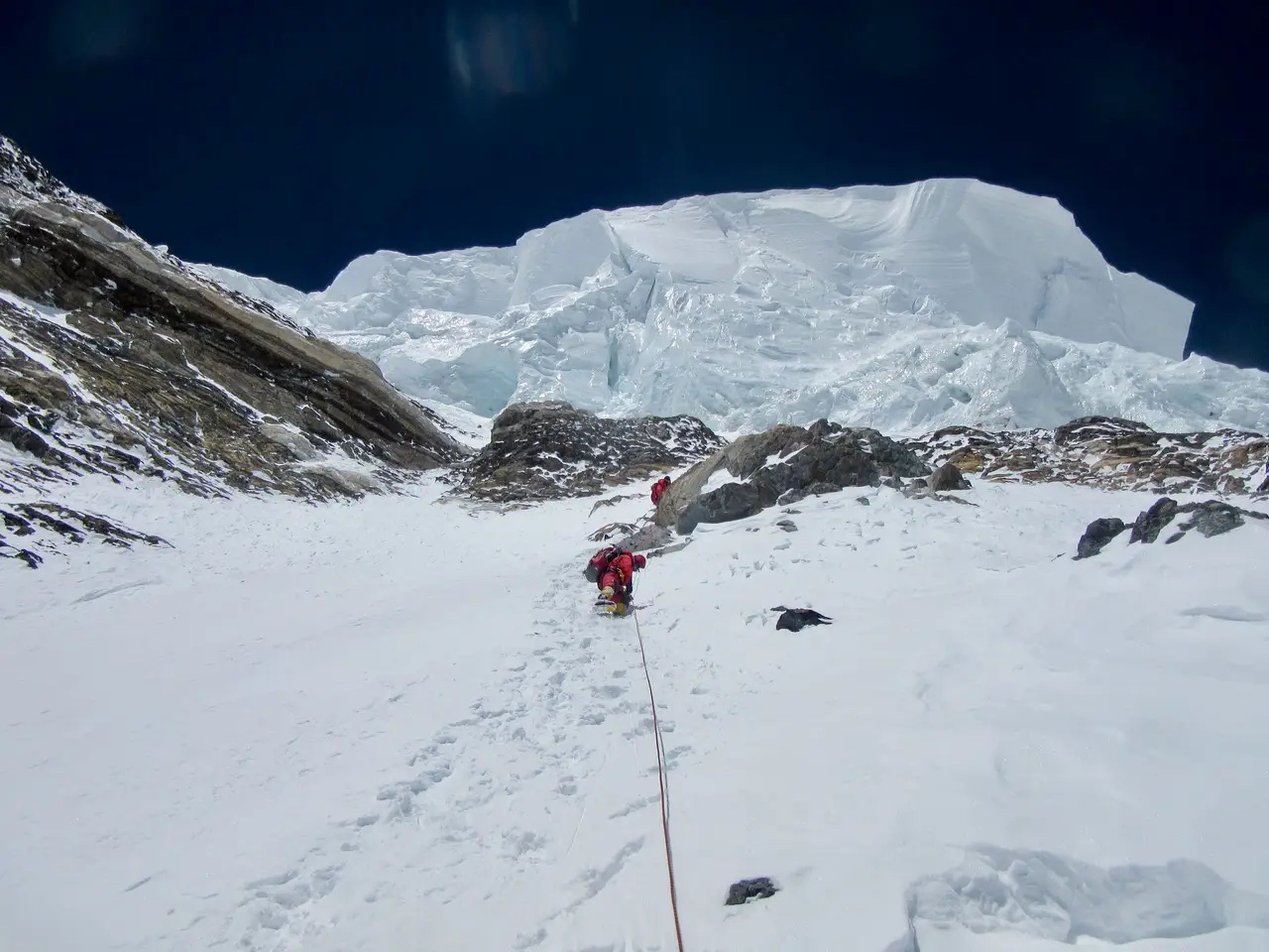 Escaladores acercándose al Cuello de Botella y a la travesía en 2014, con un gigantesco acantilado de hielo suspendido sobre ellos. 