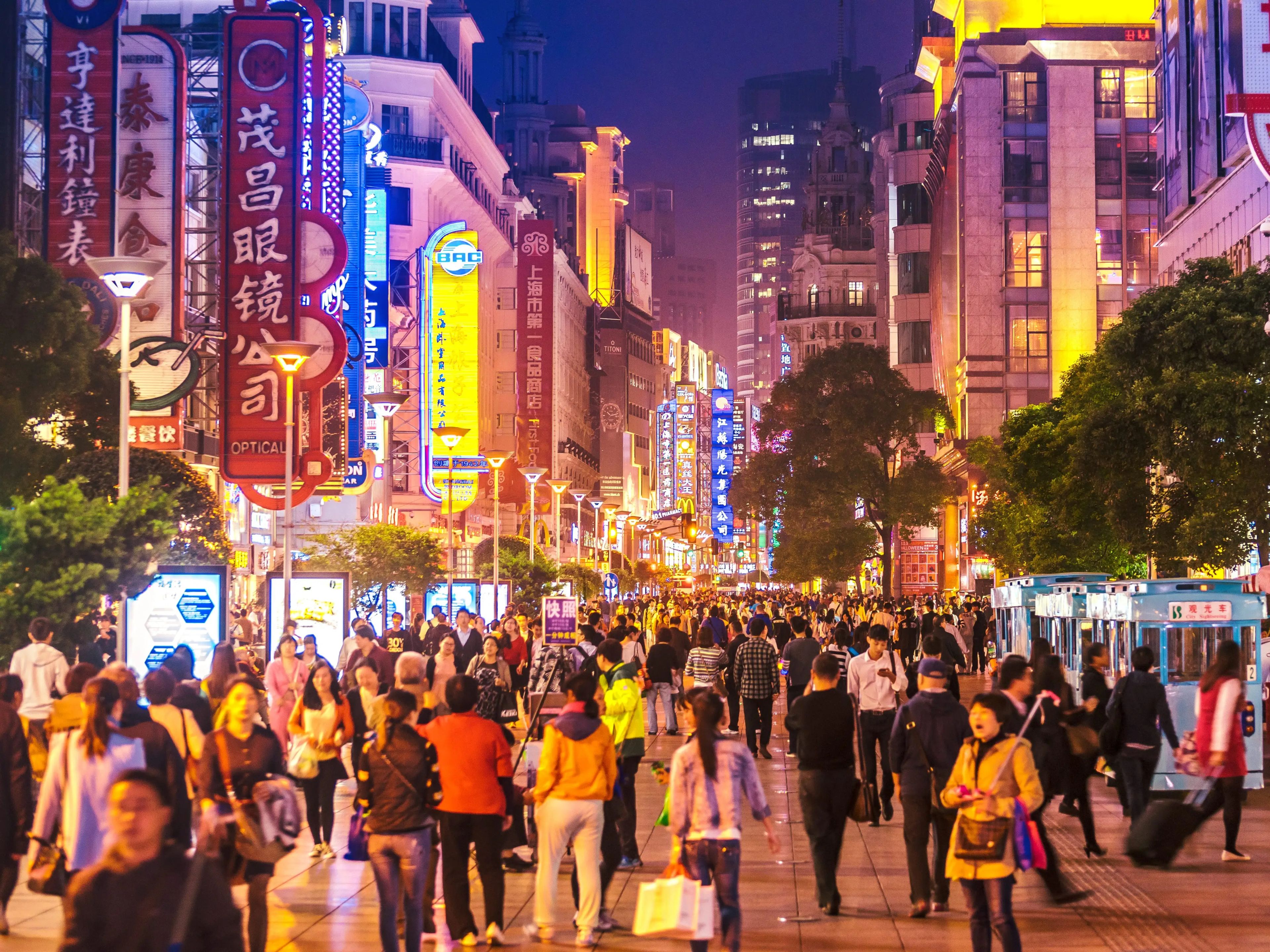 La gente camina bajo los carteles de neón de Nanjing Road. La calle es el principal distrito comercial de la ciudad y uno de los más concurridos del mundo. 