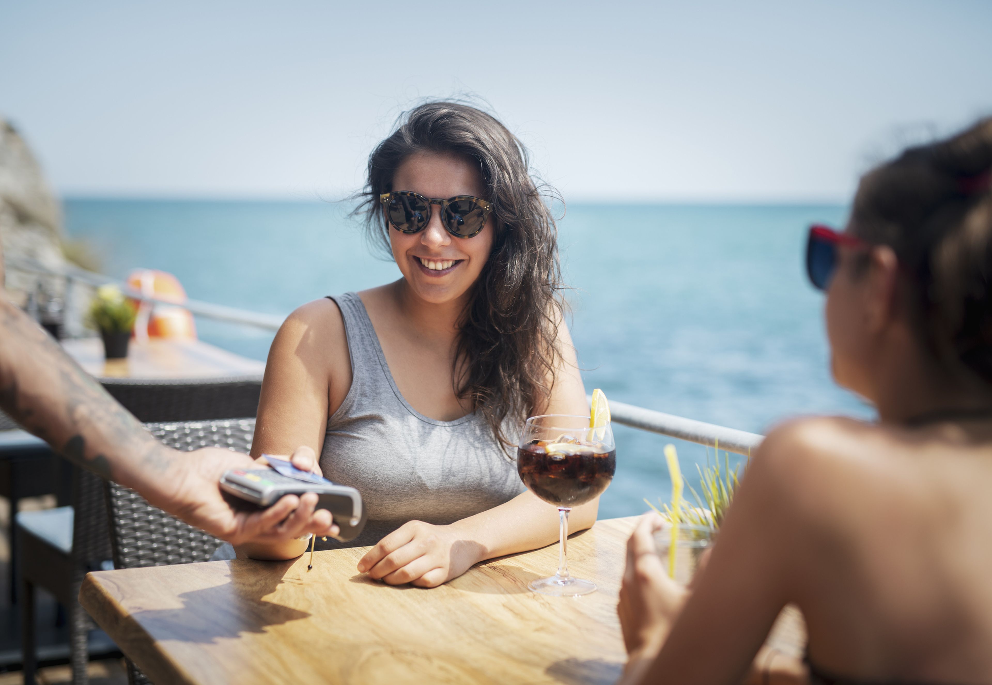 mujer bebiendo alcohol en terraza cerca del mar