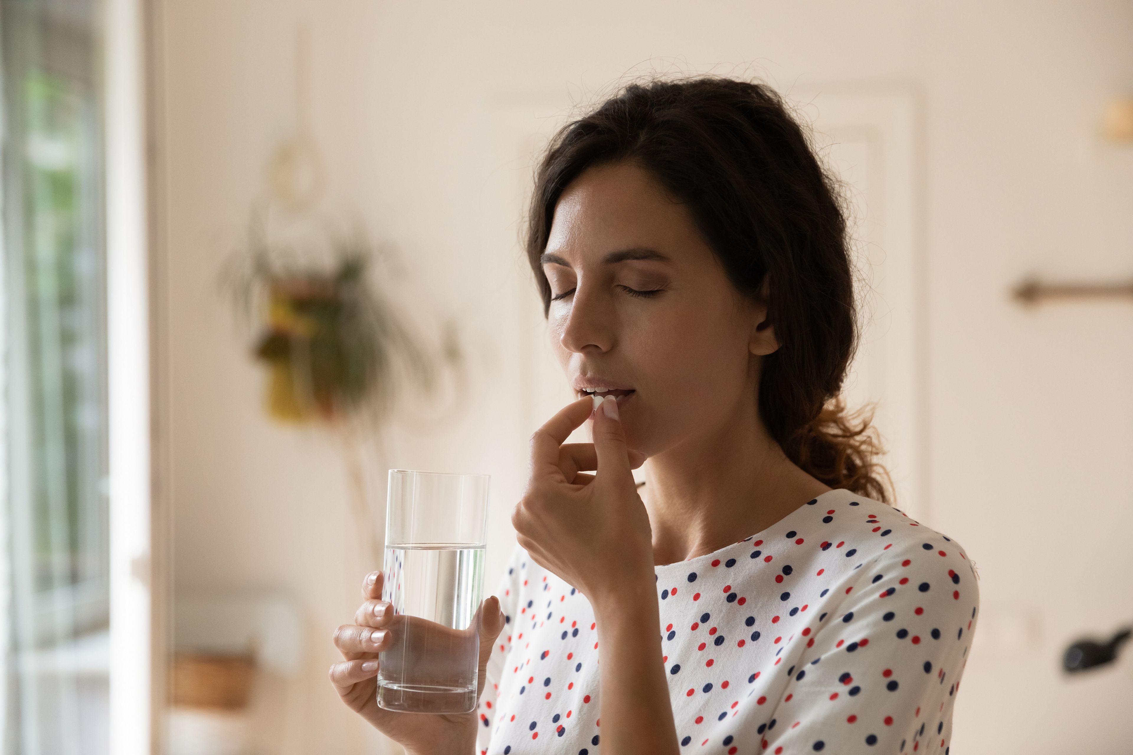 Mujer joven toma un medicamento con agua