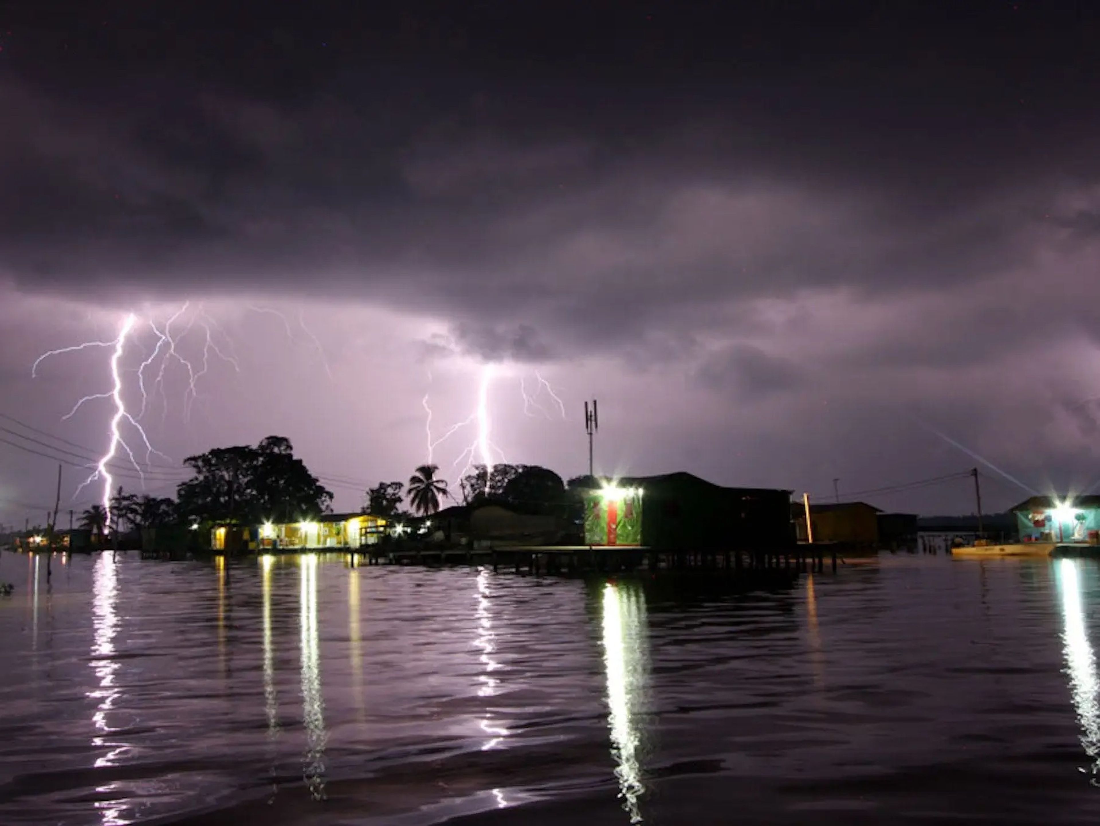 A picture of a lake-side town at night showered by several lightning bolts at once in Maracaibo.