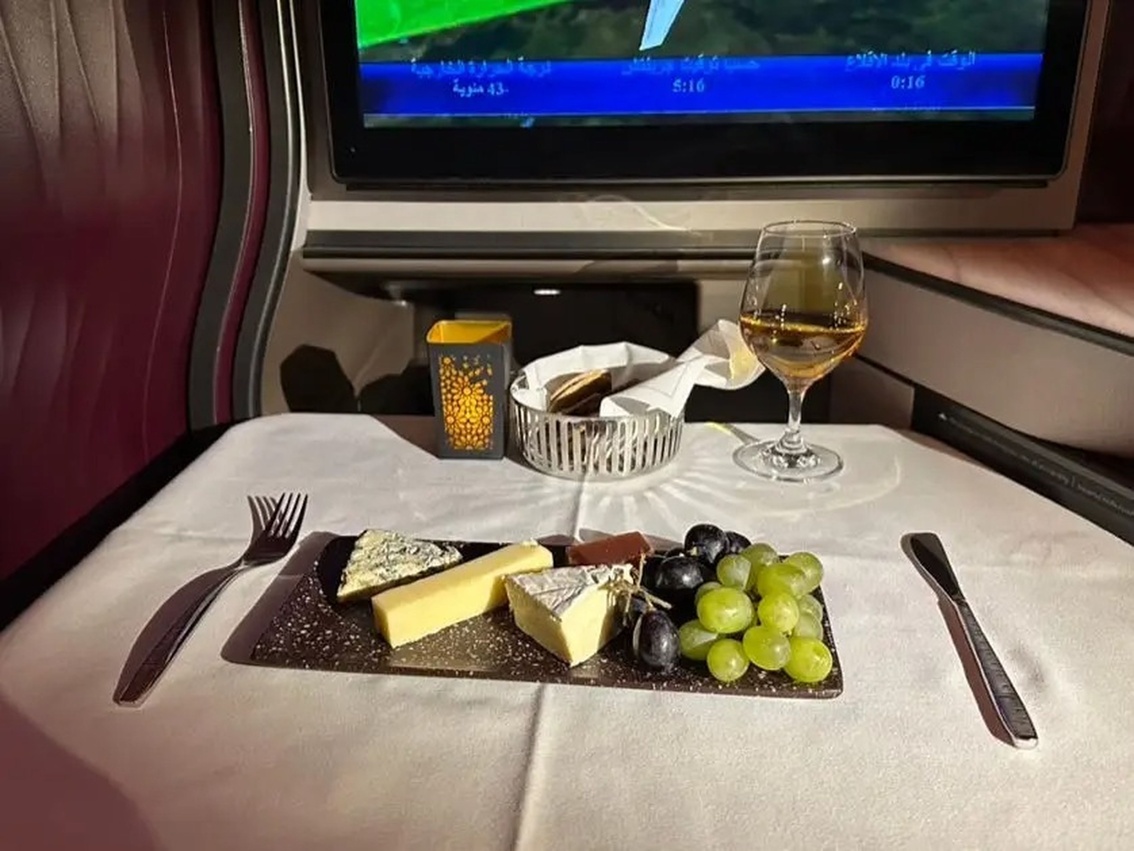 Wine and a cheese plate on an airplane table.