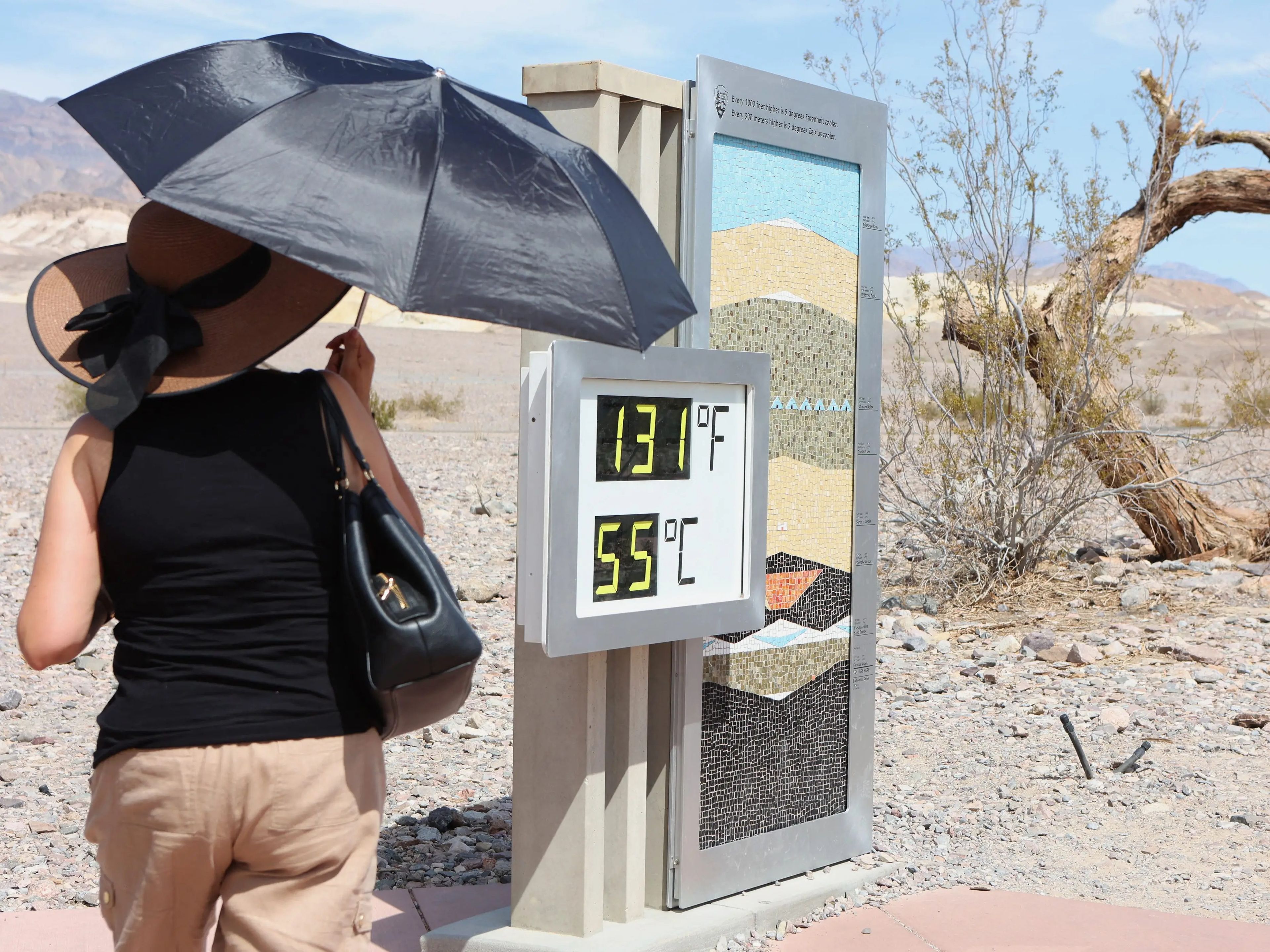 Una mujer cerca de una pantalla digital de una lectura de calor no oficial en Furnace Creek Visitor Center durante una ola de calor en el Parque Nacional Death Valley (California), el 16 de julio de 2023.