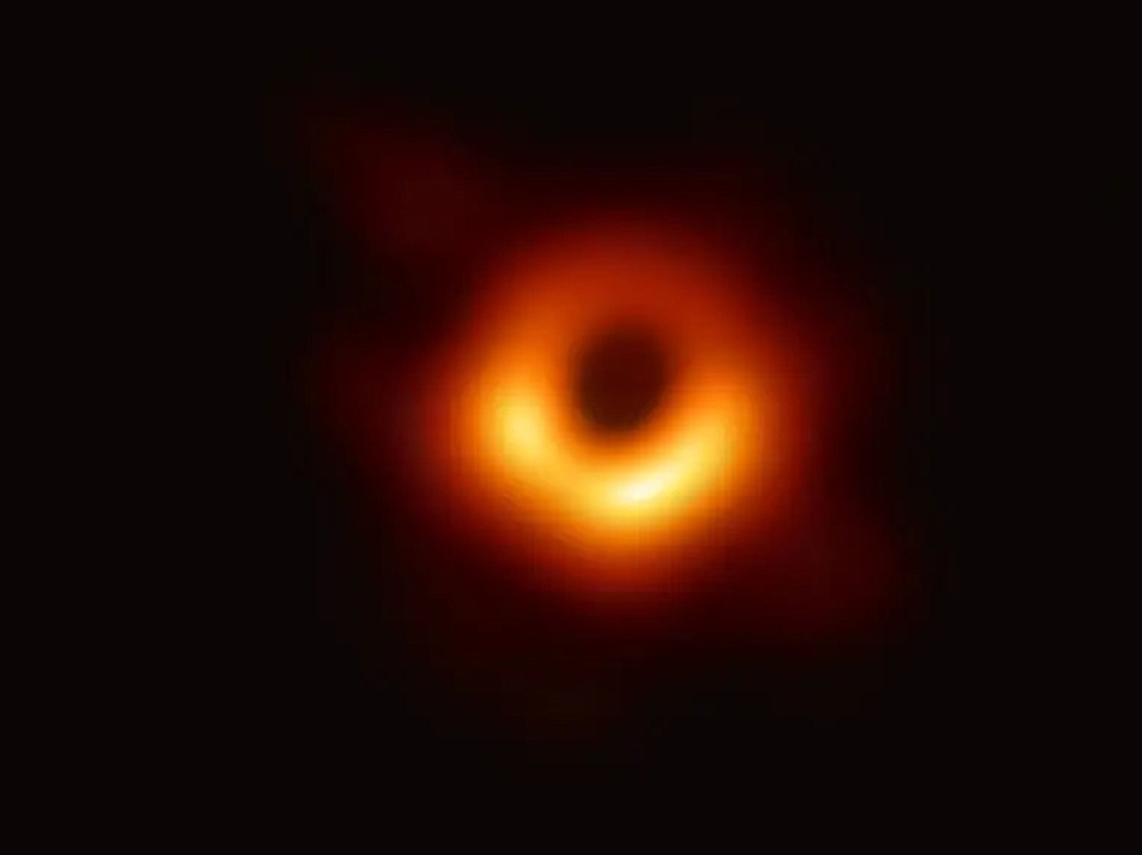 La primera imagen de un agujero negro. El anillo naranja es una nube de material sobrecalentado que es succionado por el agujero negro.