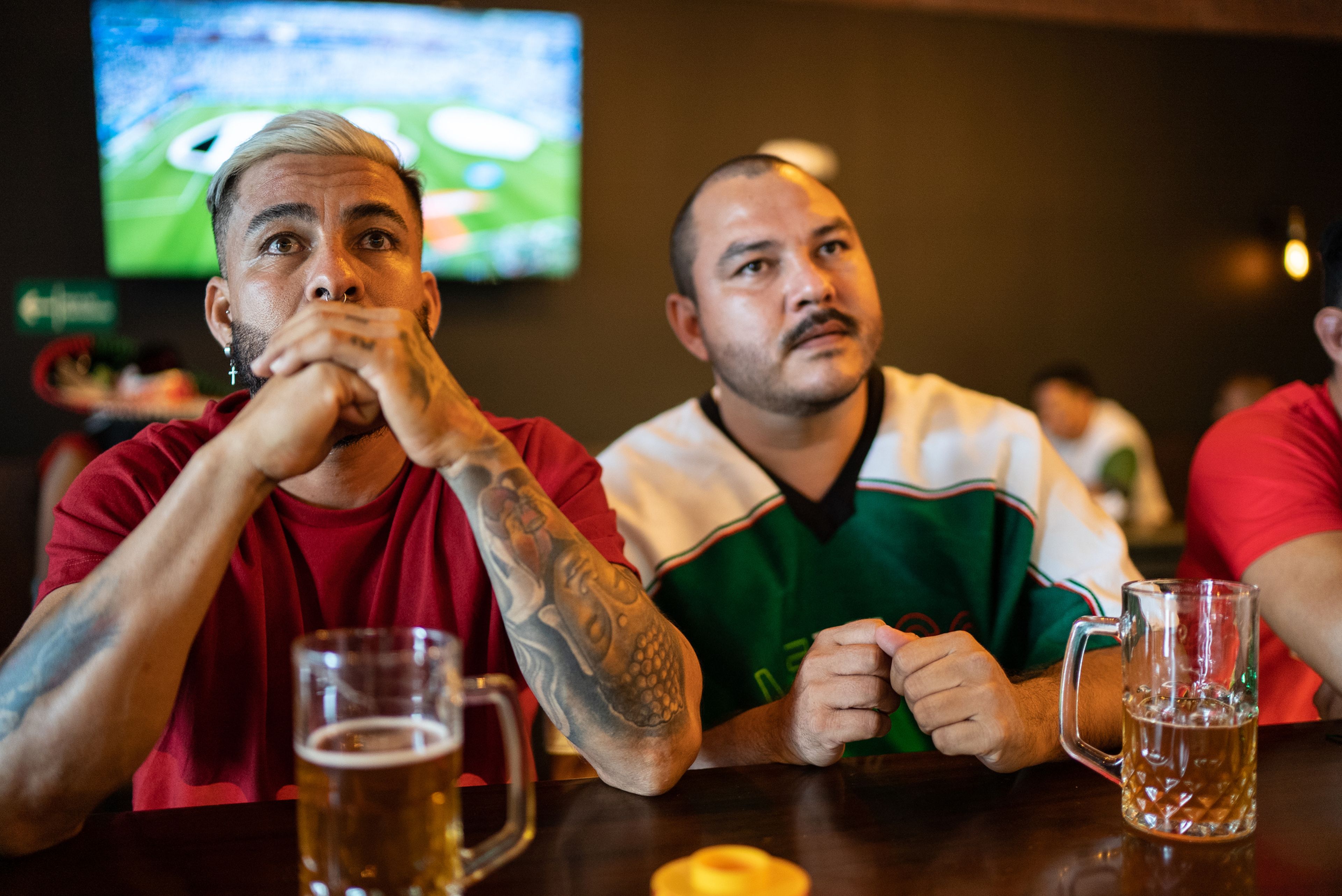 Amigos ven el fútbol en la televisión de un bar, con cerveza