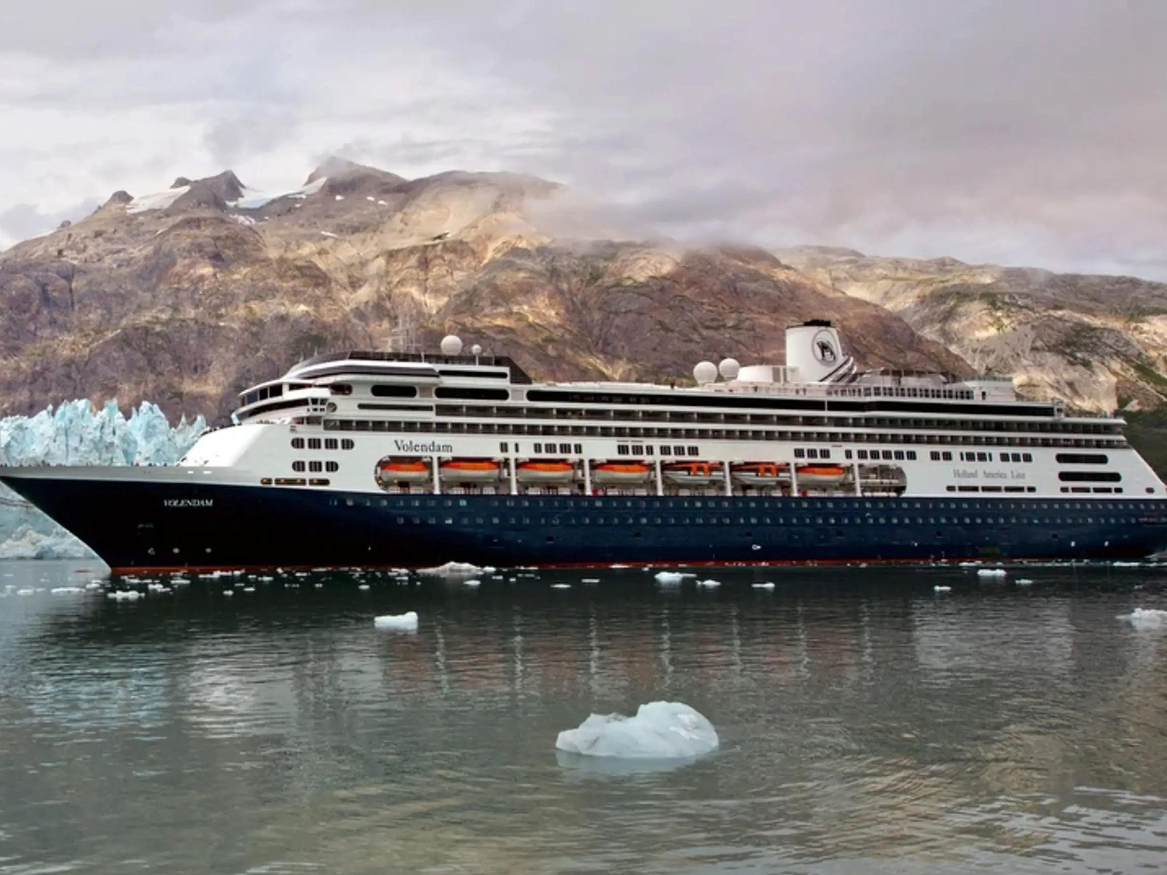 The Holland America Volendam sailing on water near icebergs and land