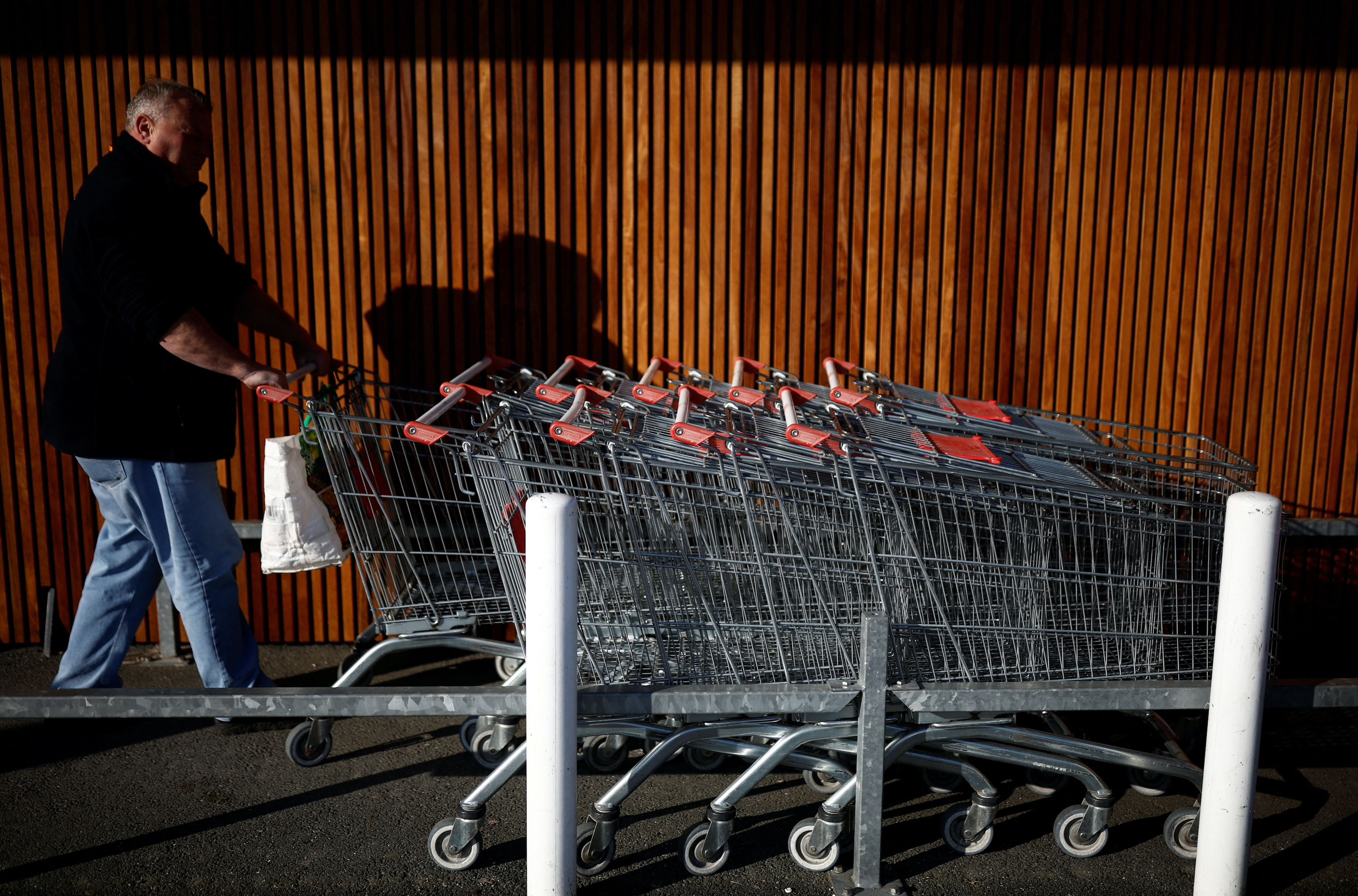 Un hombre con carritos de supermercado para hacer la compra en inflación