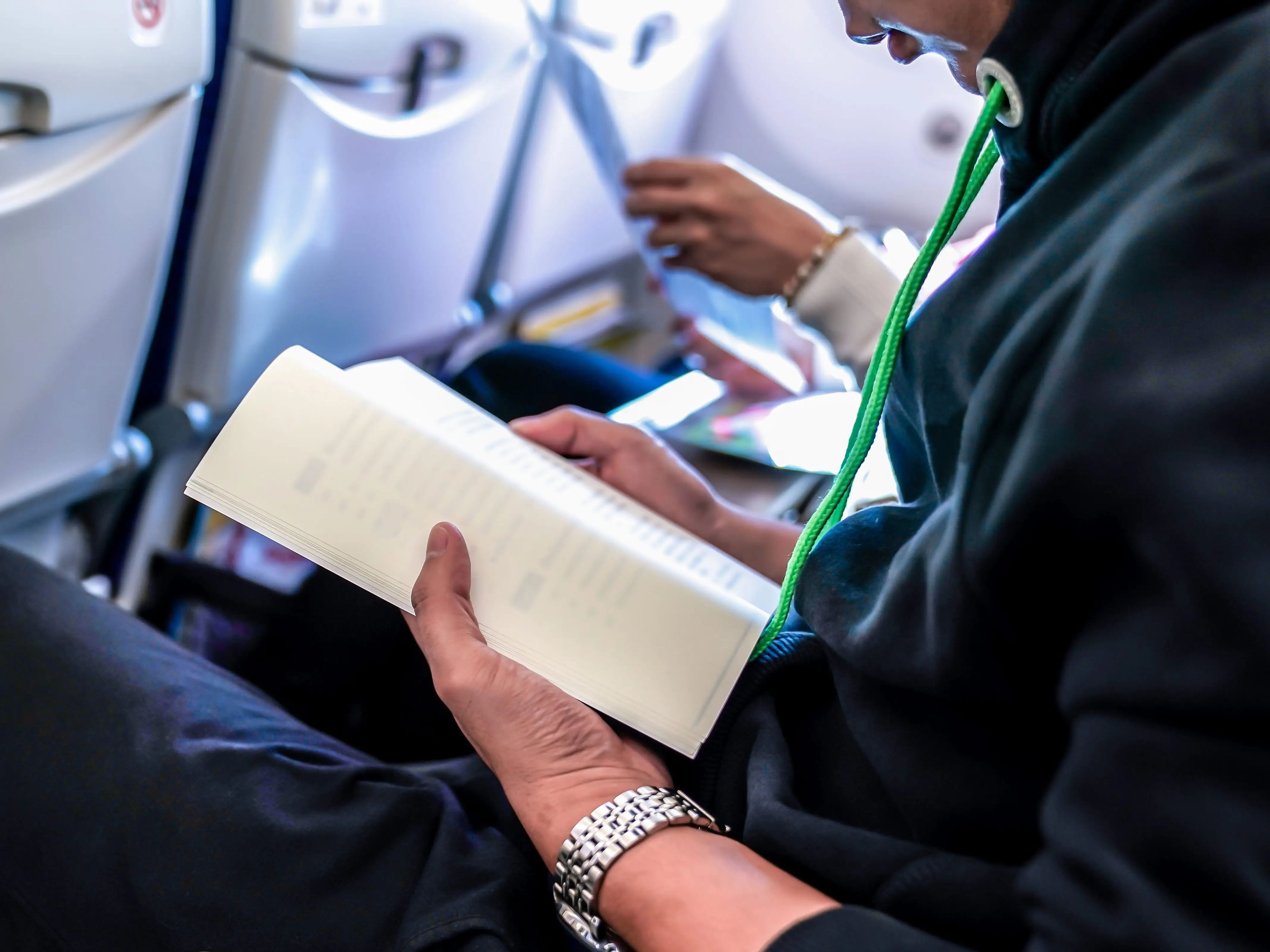 A man reading a book on a plane