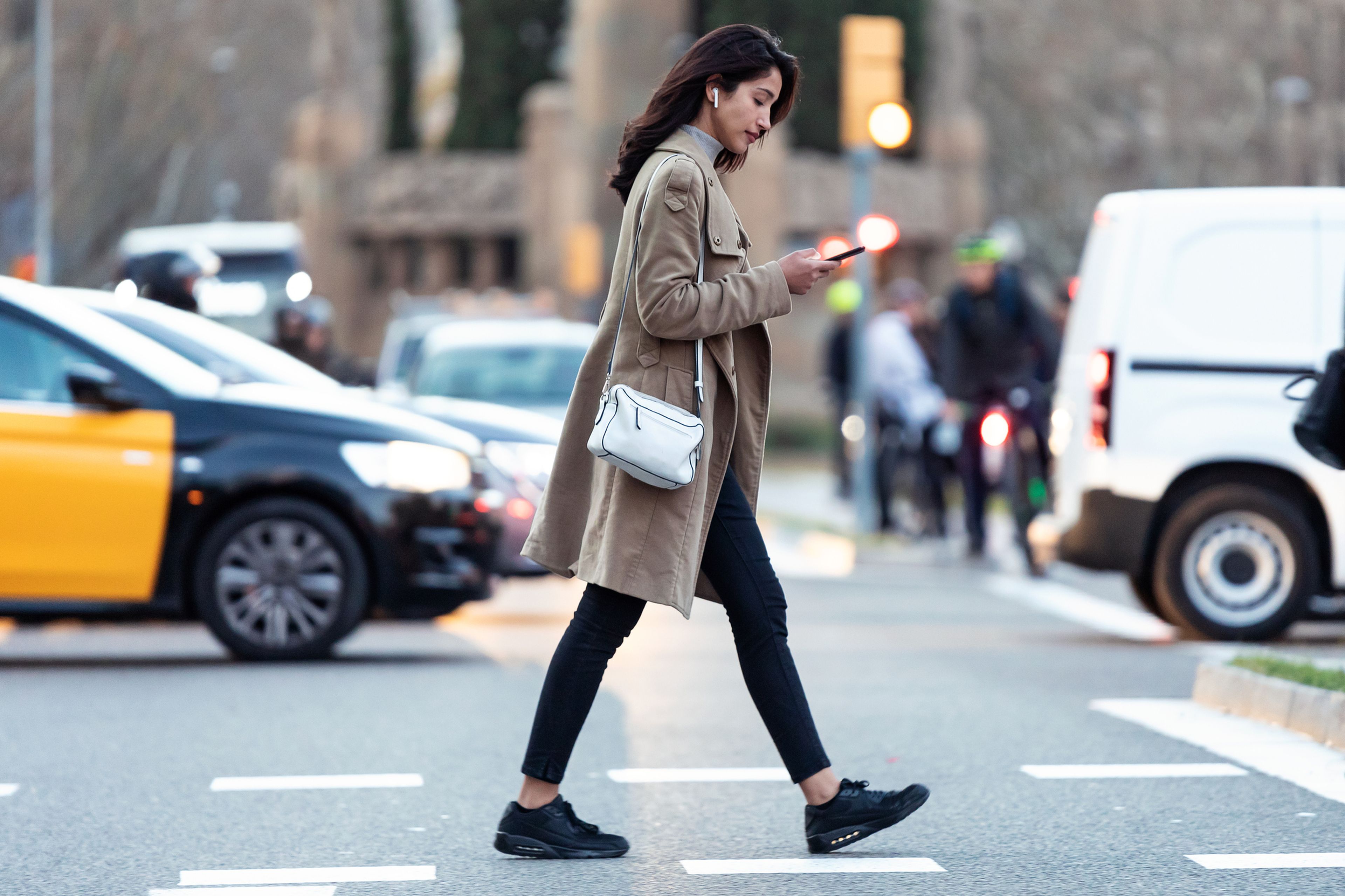 Mujer cruzando paso de peatones mirando el móvil