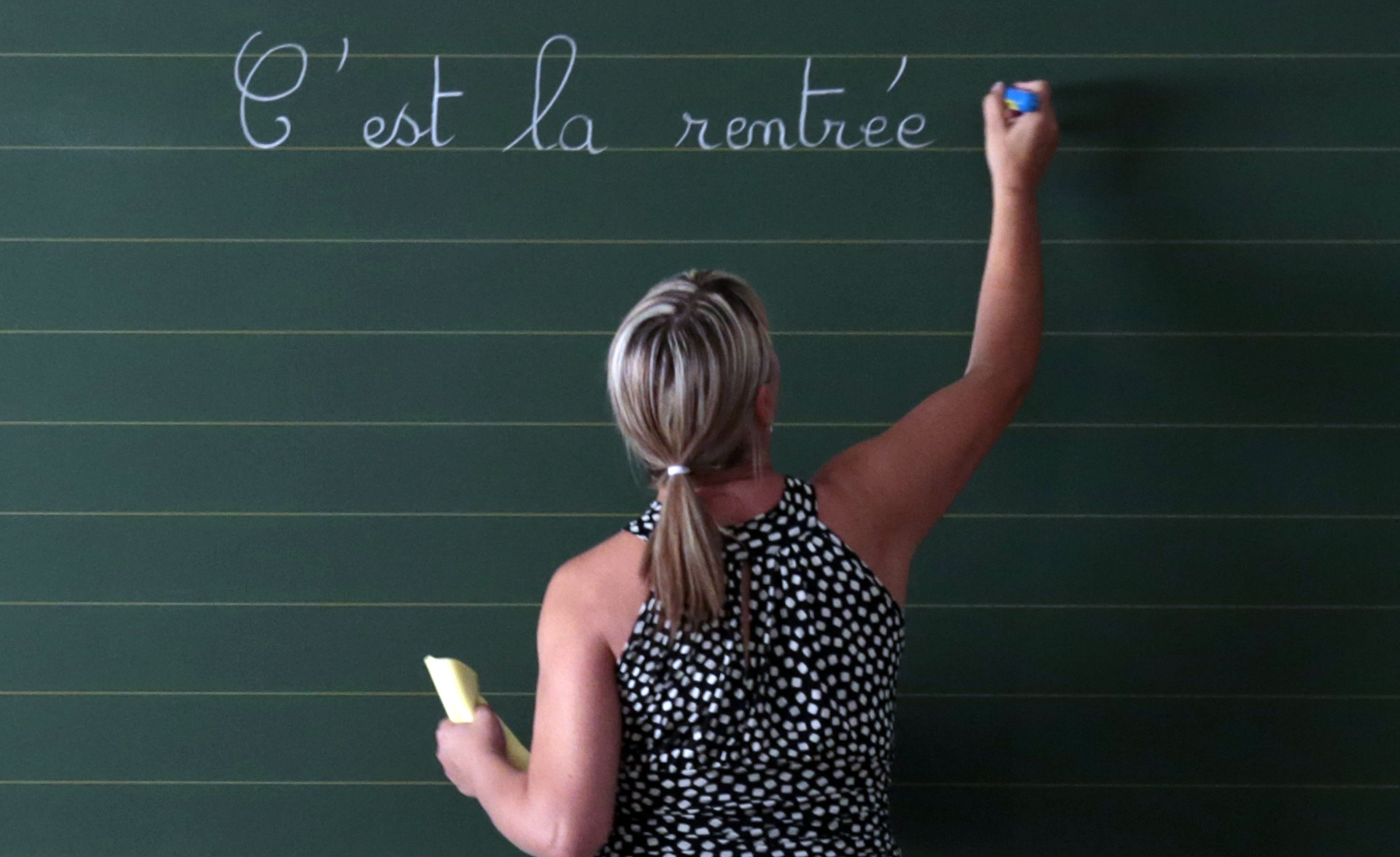 Una profesora de francés escribe en una pizarra