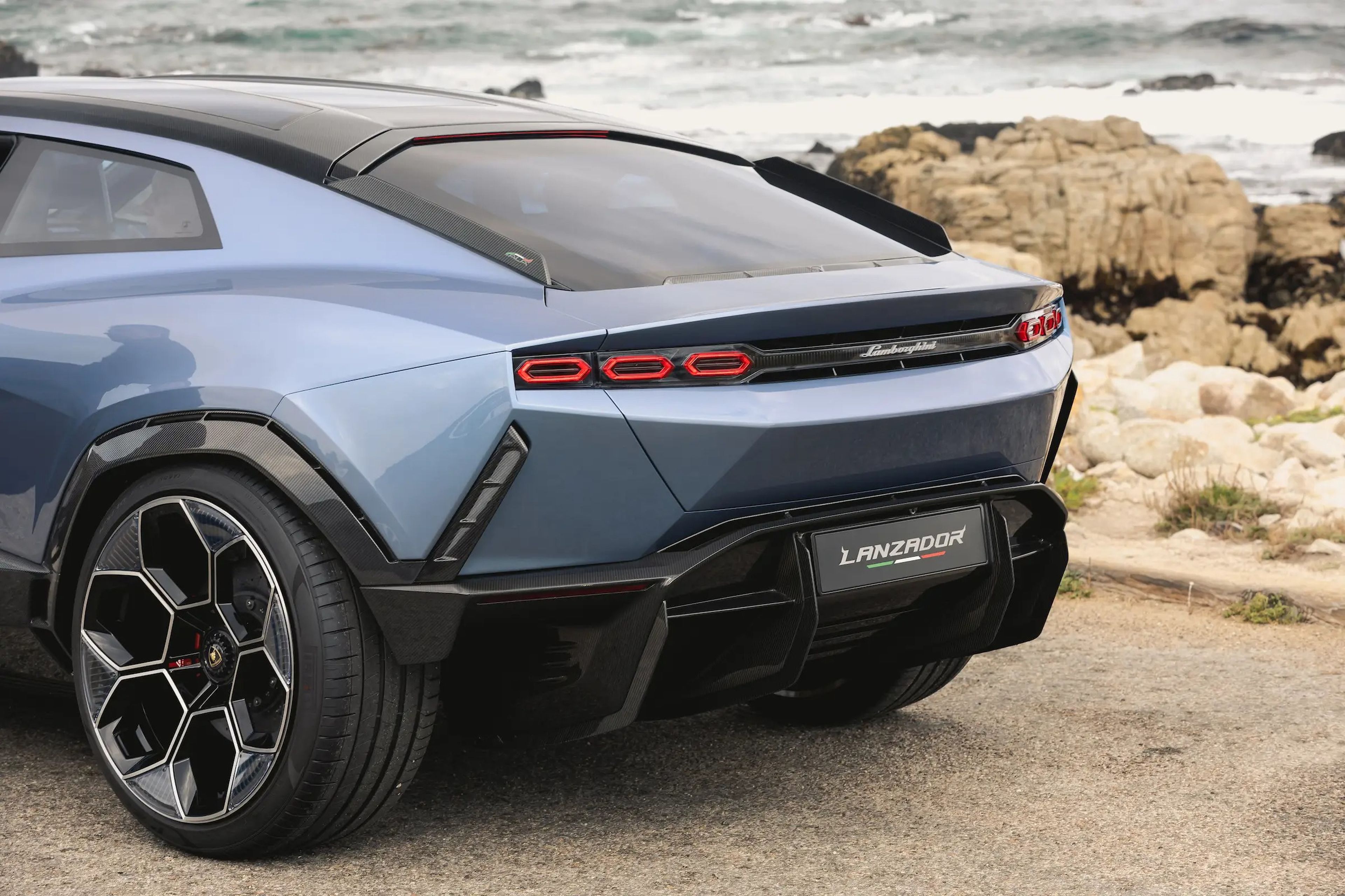 La parte trasera del prototipo Lamborghini Lanzador, con una playa rocosa al fondo. 