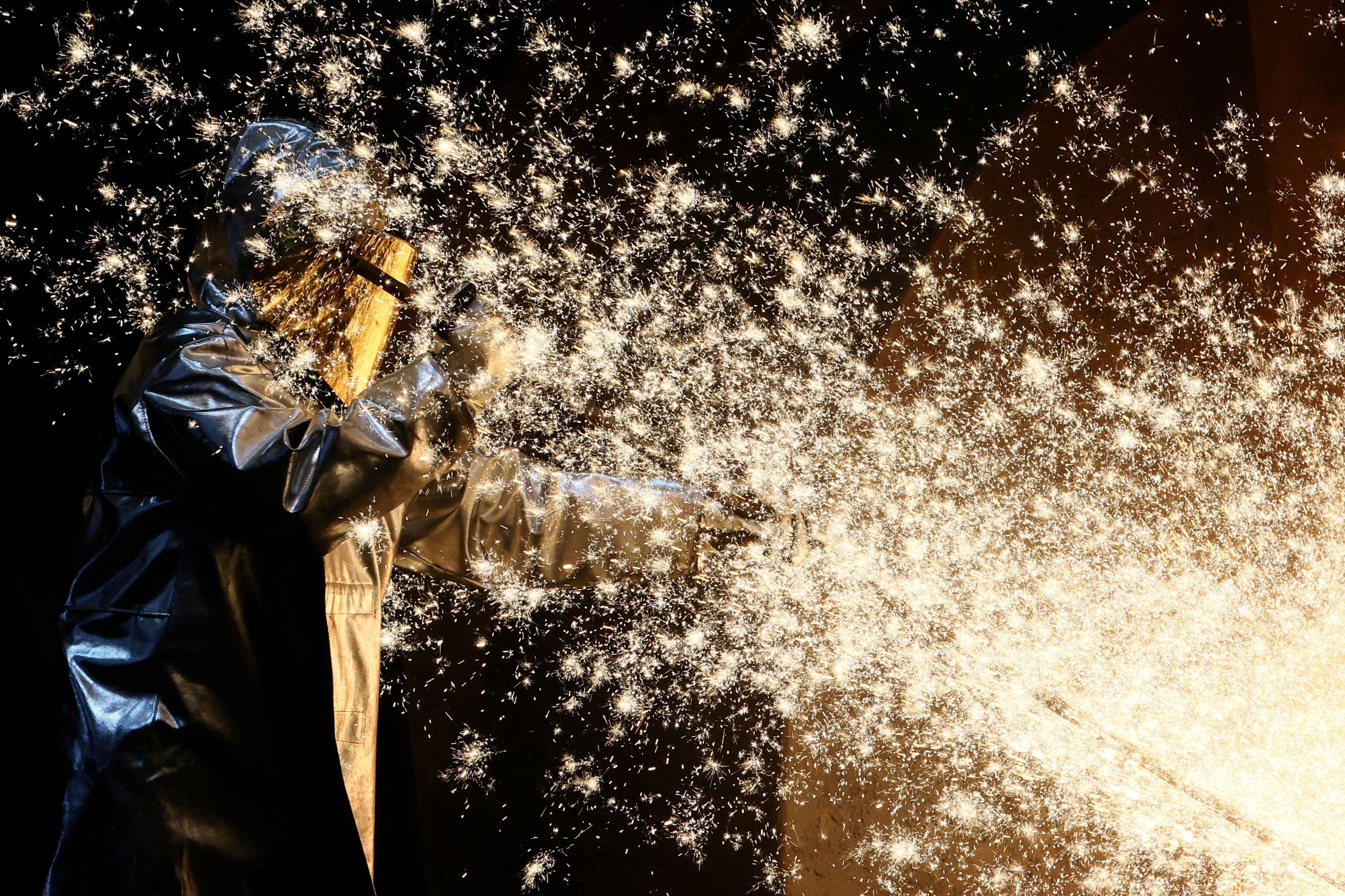 Un trabajador siderúrgico de ThyssenKrupp junto a las chispas de hierro que salen de un alto horno en una fábrica de acero de ThyssenKrupp en Duisburgo.