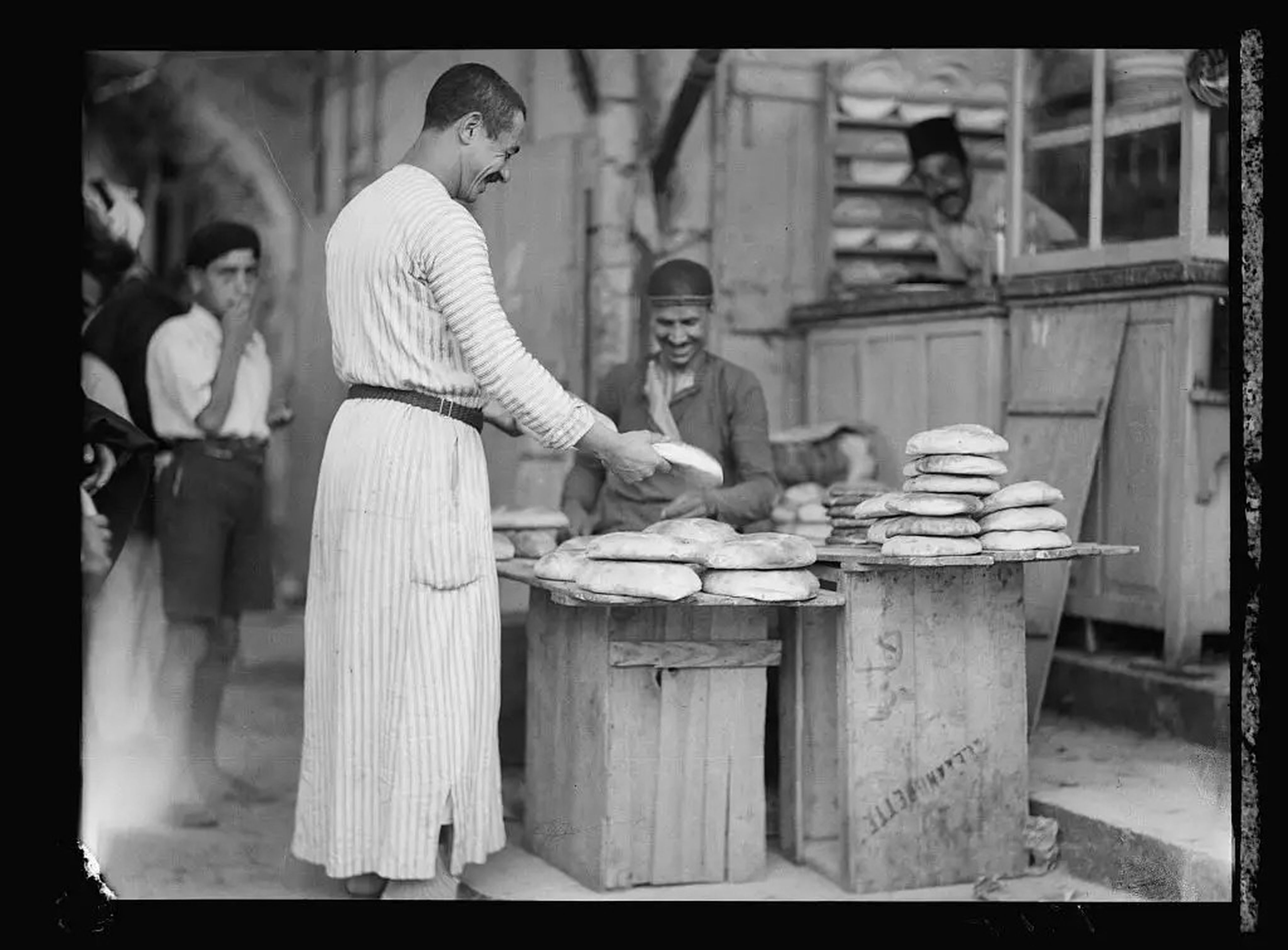 Un panadero palestino vende pan a uno de sus vecinos.