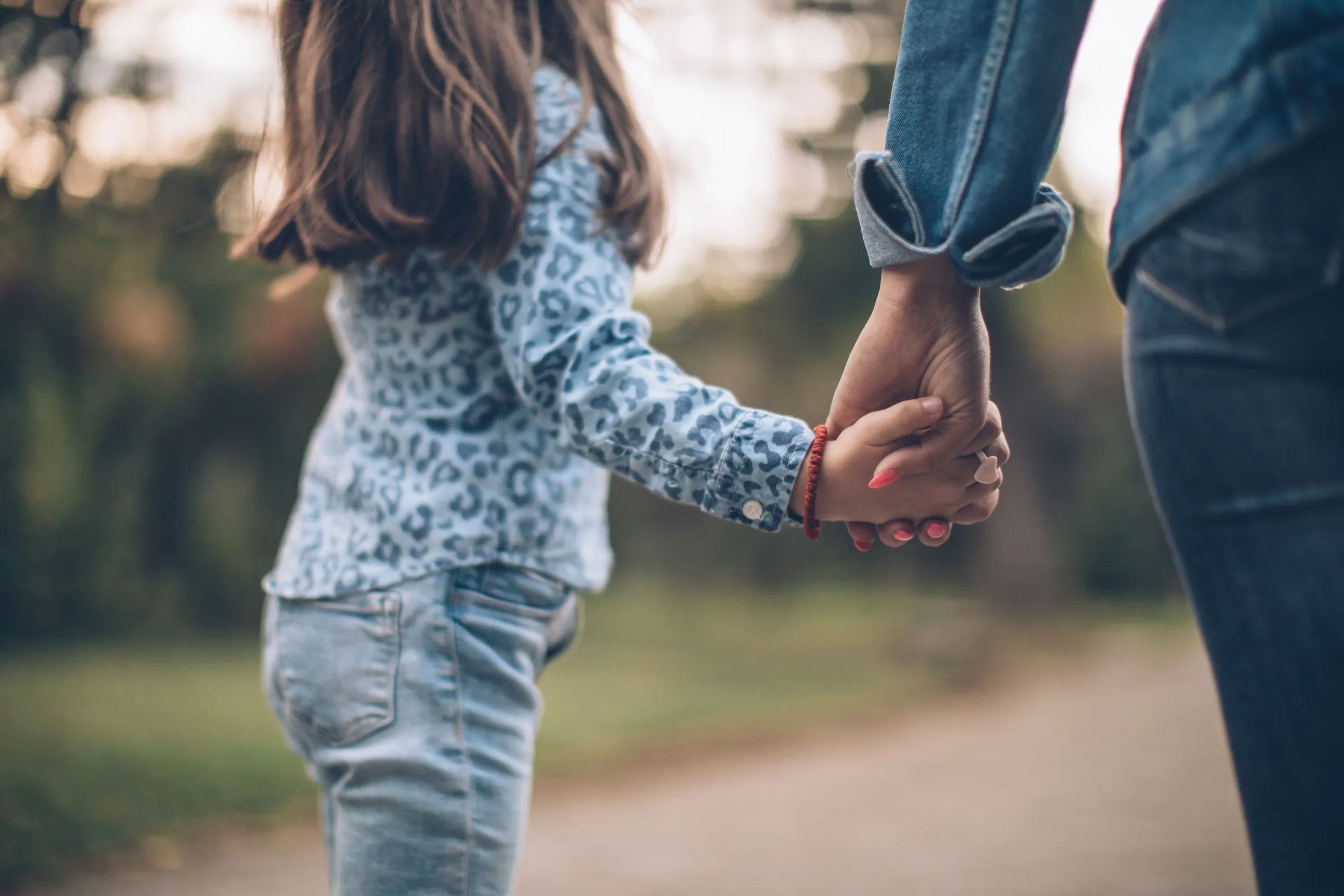 Close-up image of mother and daughter holding hands while walking outside