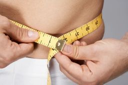 a close up of a person measuring their waist size 