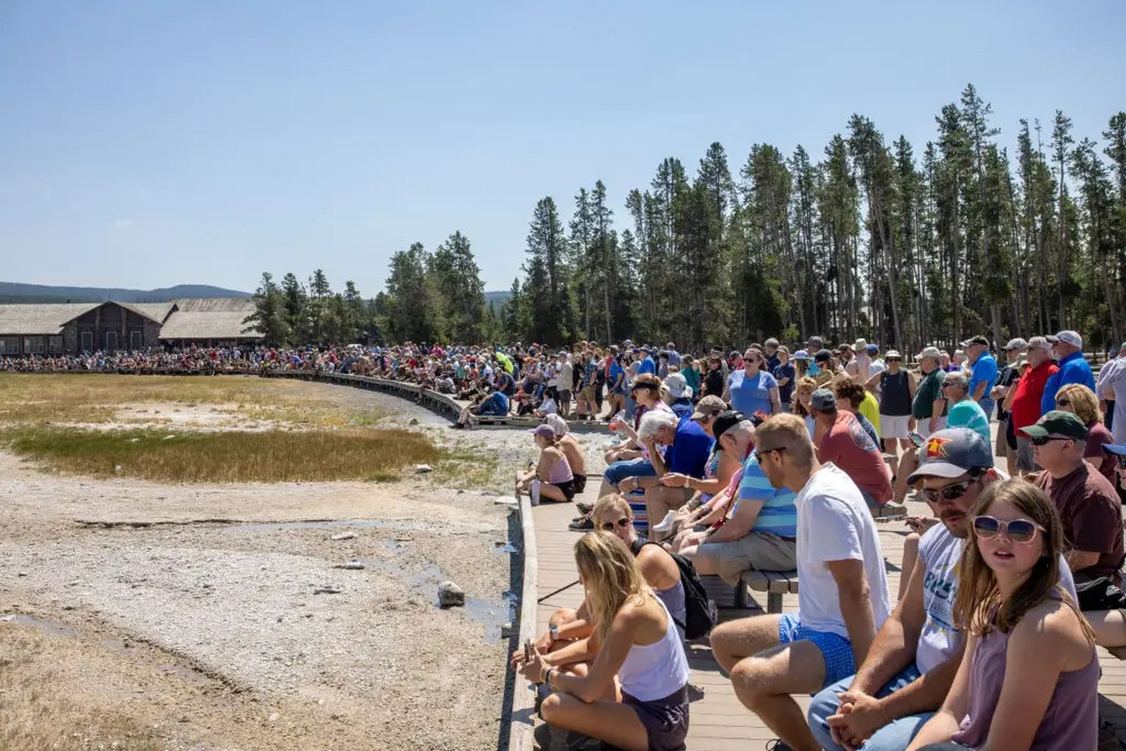 Cientos de turistas se concentran en un mirador para contemplar la erupción del géiser Old Faithful el 14 de julio de 2021 en el Parque Nacional de Yellowstone, Wyoming.