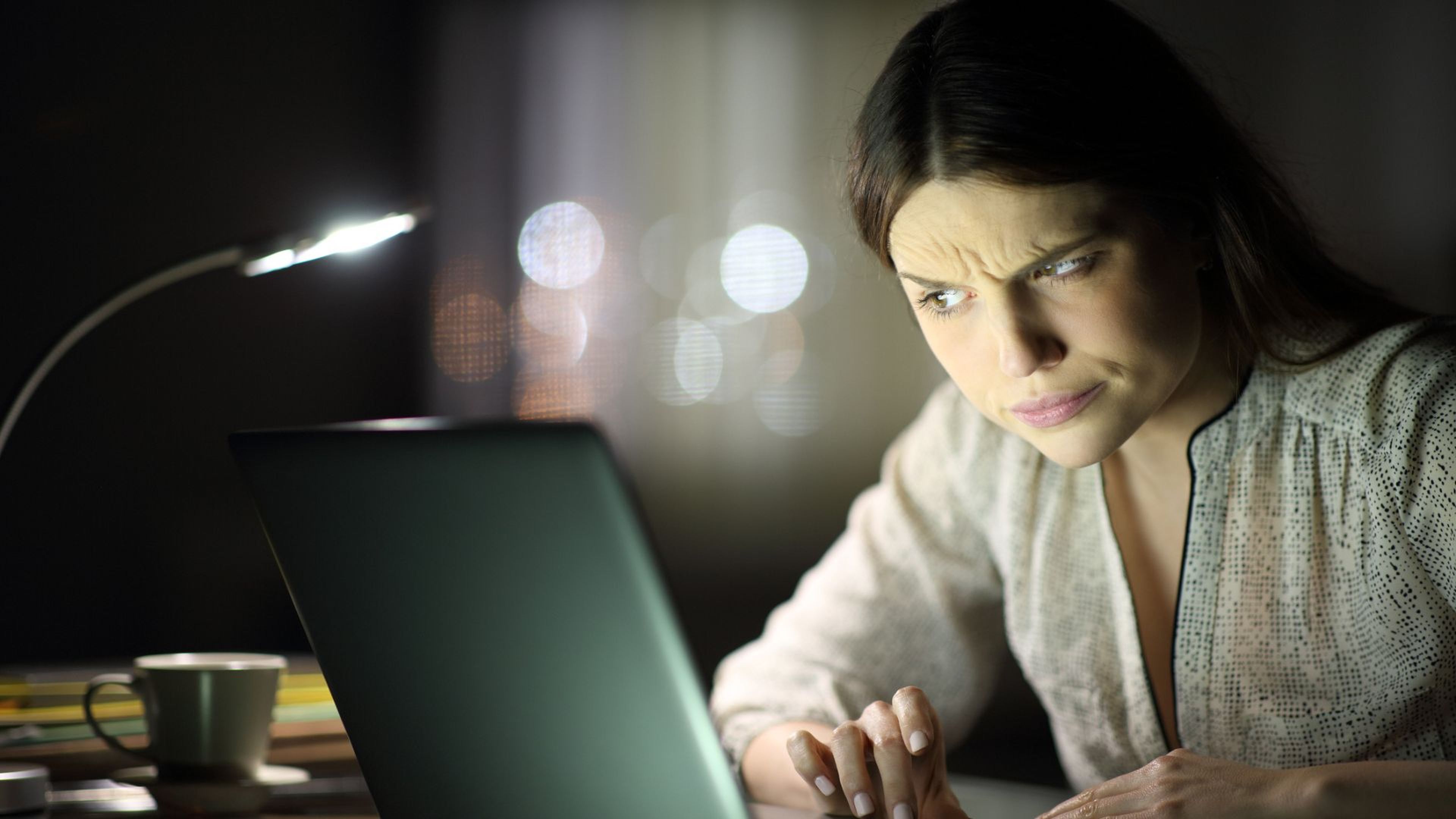 Una mujer mira el ordenador con cara de sospecha.