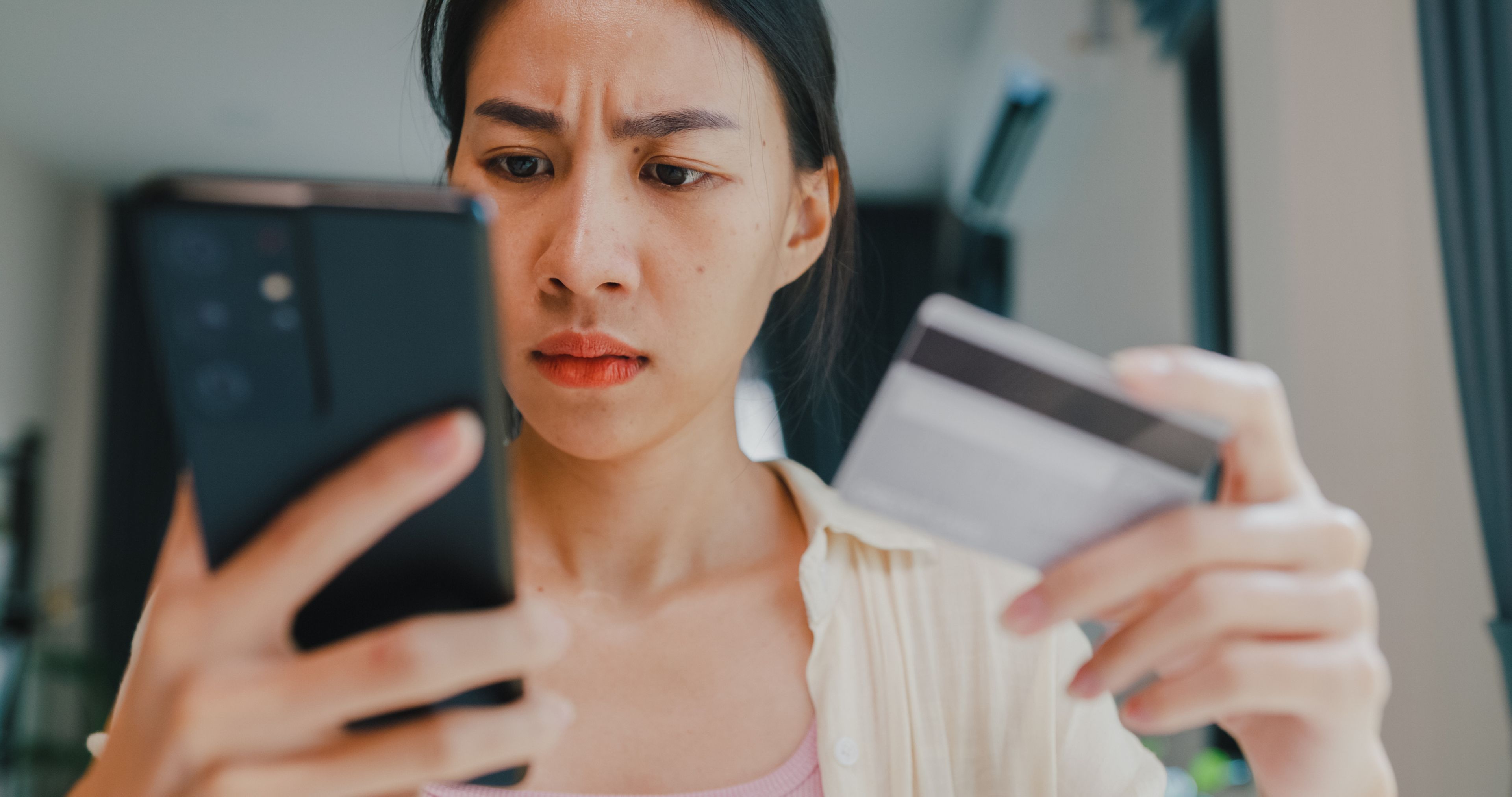 Mujer sosteniendo su teléfono y tarjeta de crédito