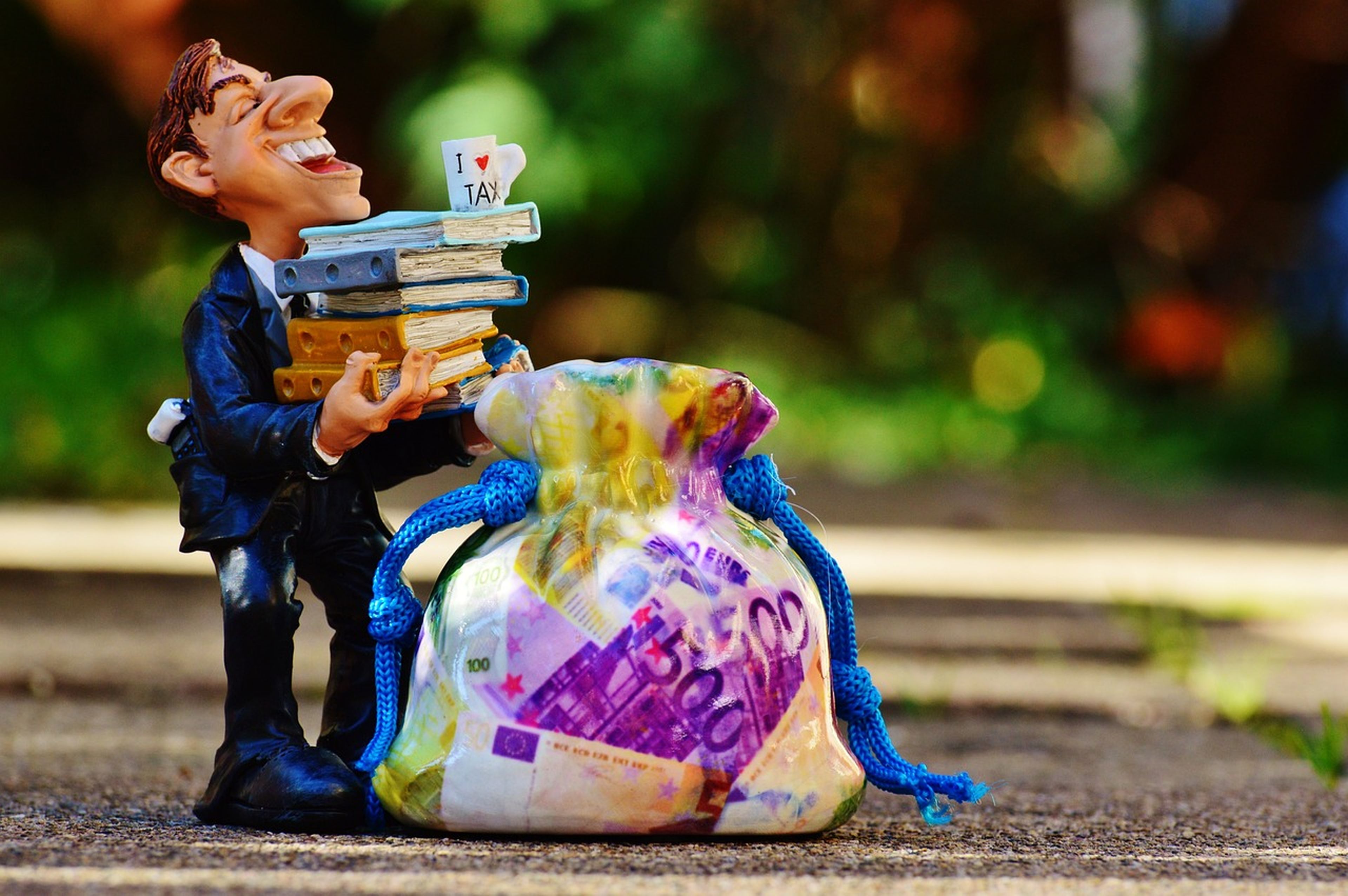 Un muñeco sujeta varios libros de cuentas y un gran saco con billetes de euros.