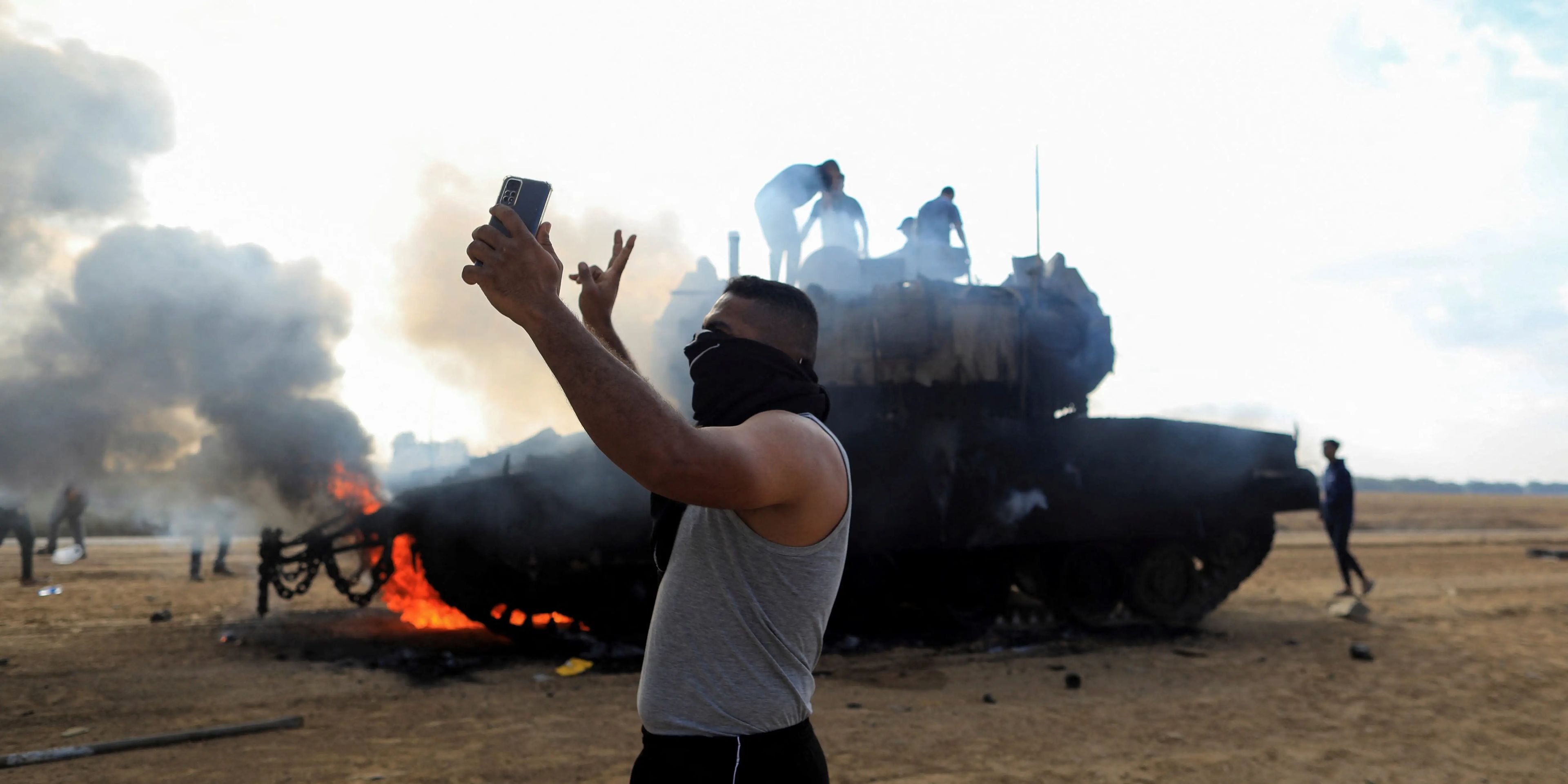 Un palestino se hace un selfie delante de un vehículo militar israelí en llamas tras ser alcanzado por tiradores palestinos infiltrados en zonas del sur de Israel.