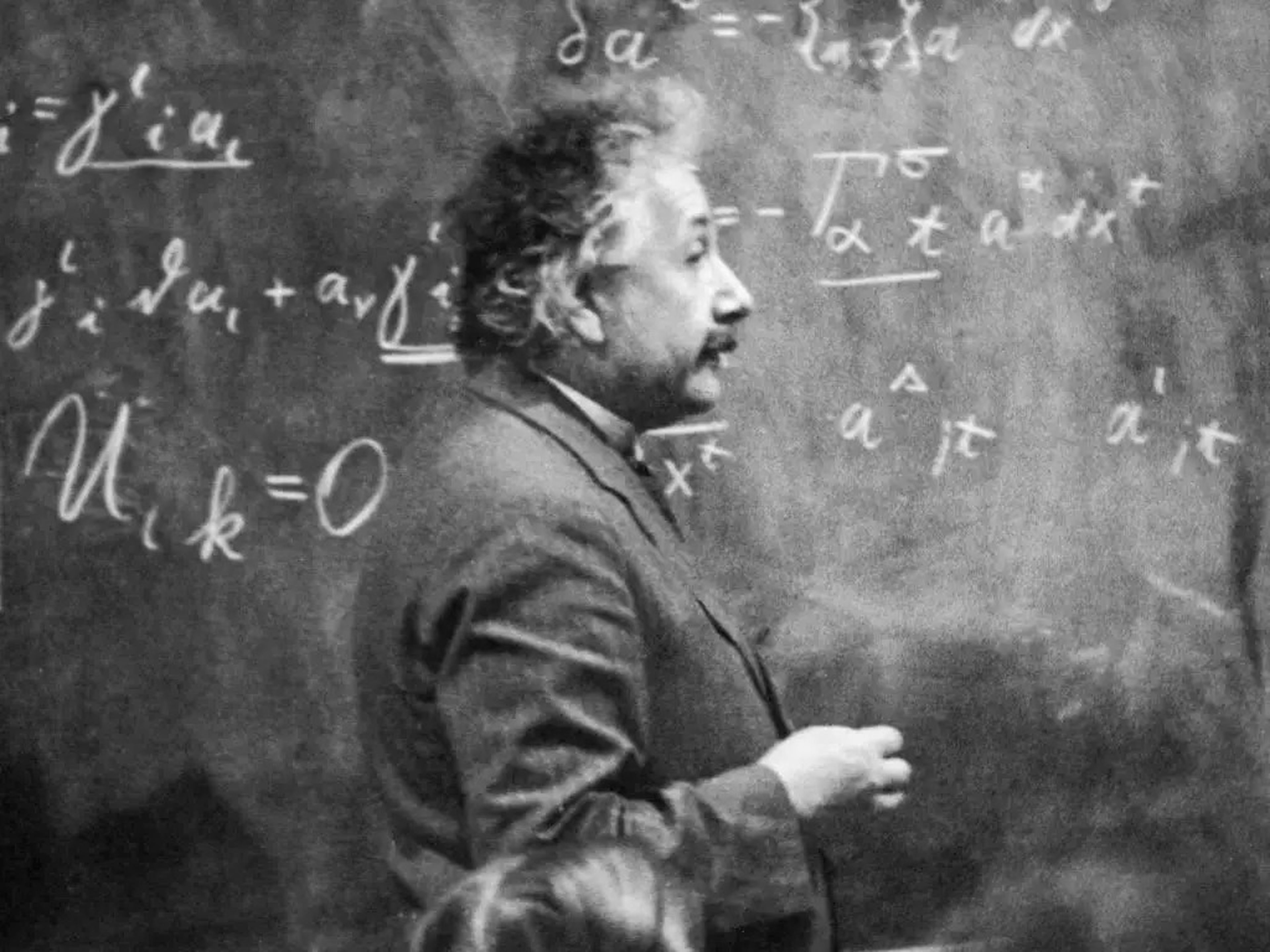 Photo of Albert Einstein in front of a chalkboard.