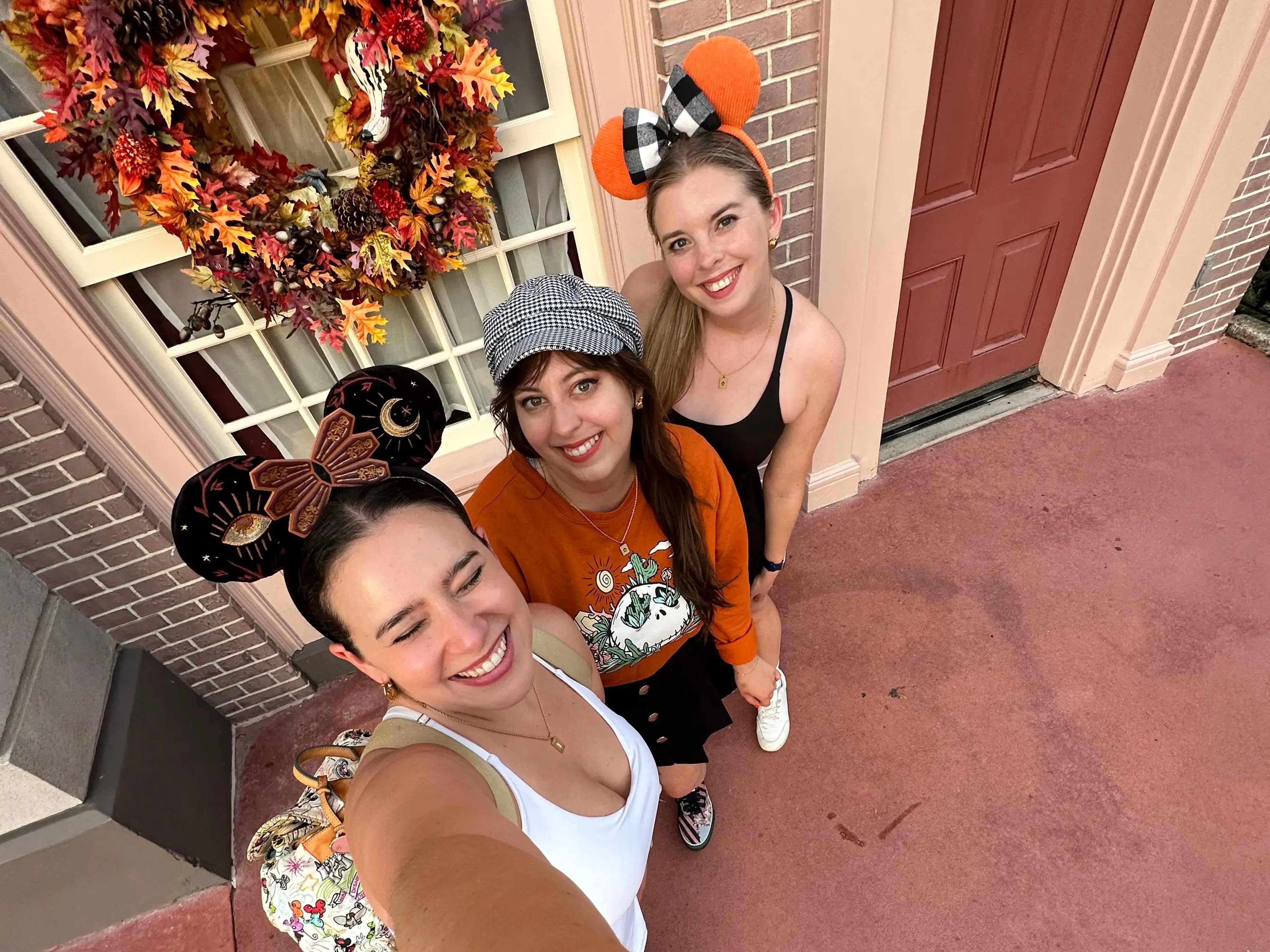 Three people at Disney World with fall-themed Mickey ears.