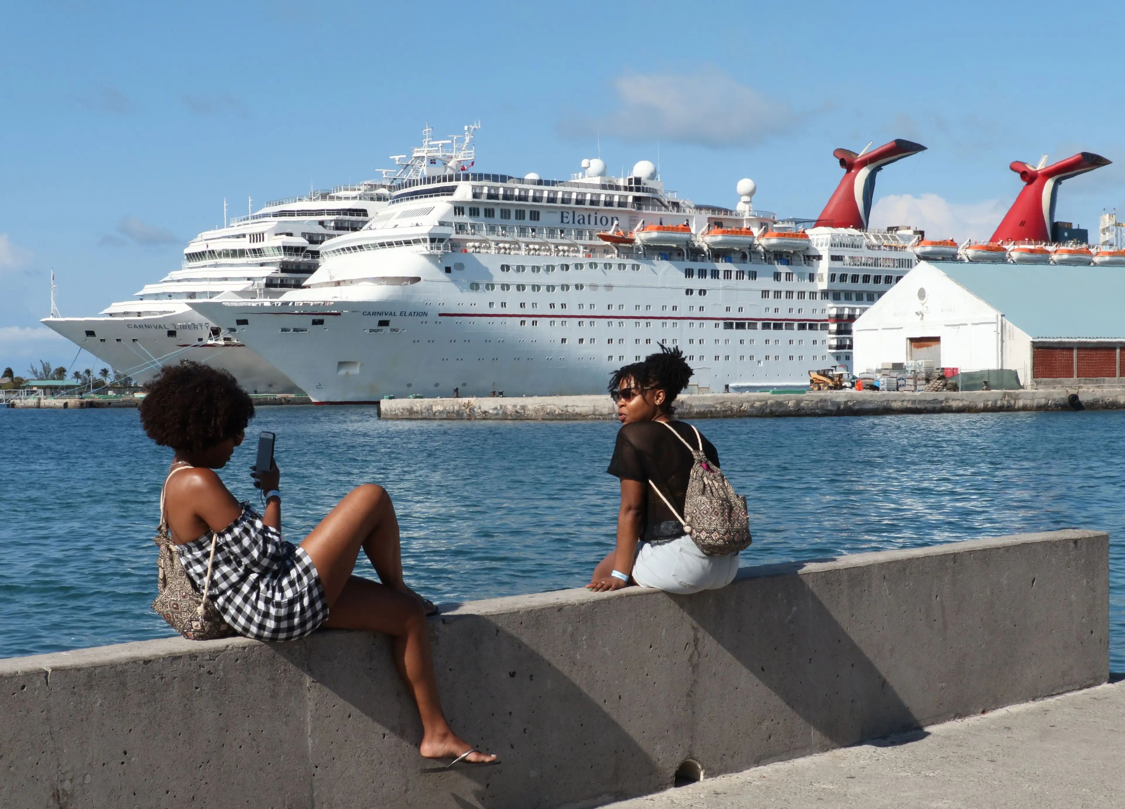 Two ladies take pictures in front of the Carnival cruise ship Elation in Nassau, Bahamas on April 29, 2019.