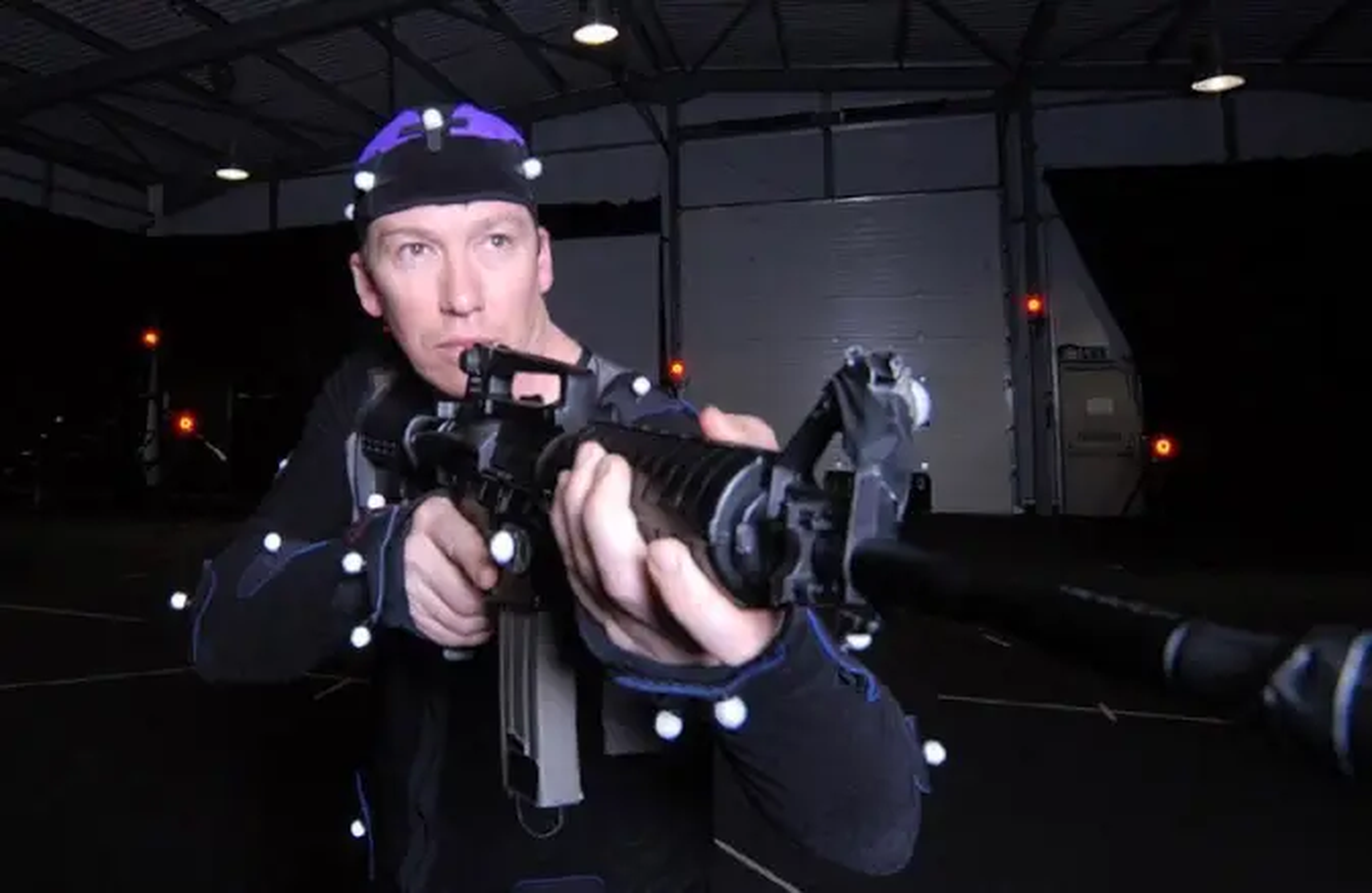 Steen Young en un traje de captura de movimiento sosteniendo una pistola.