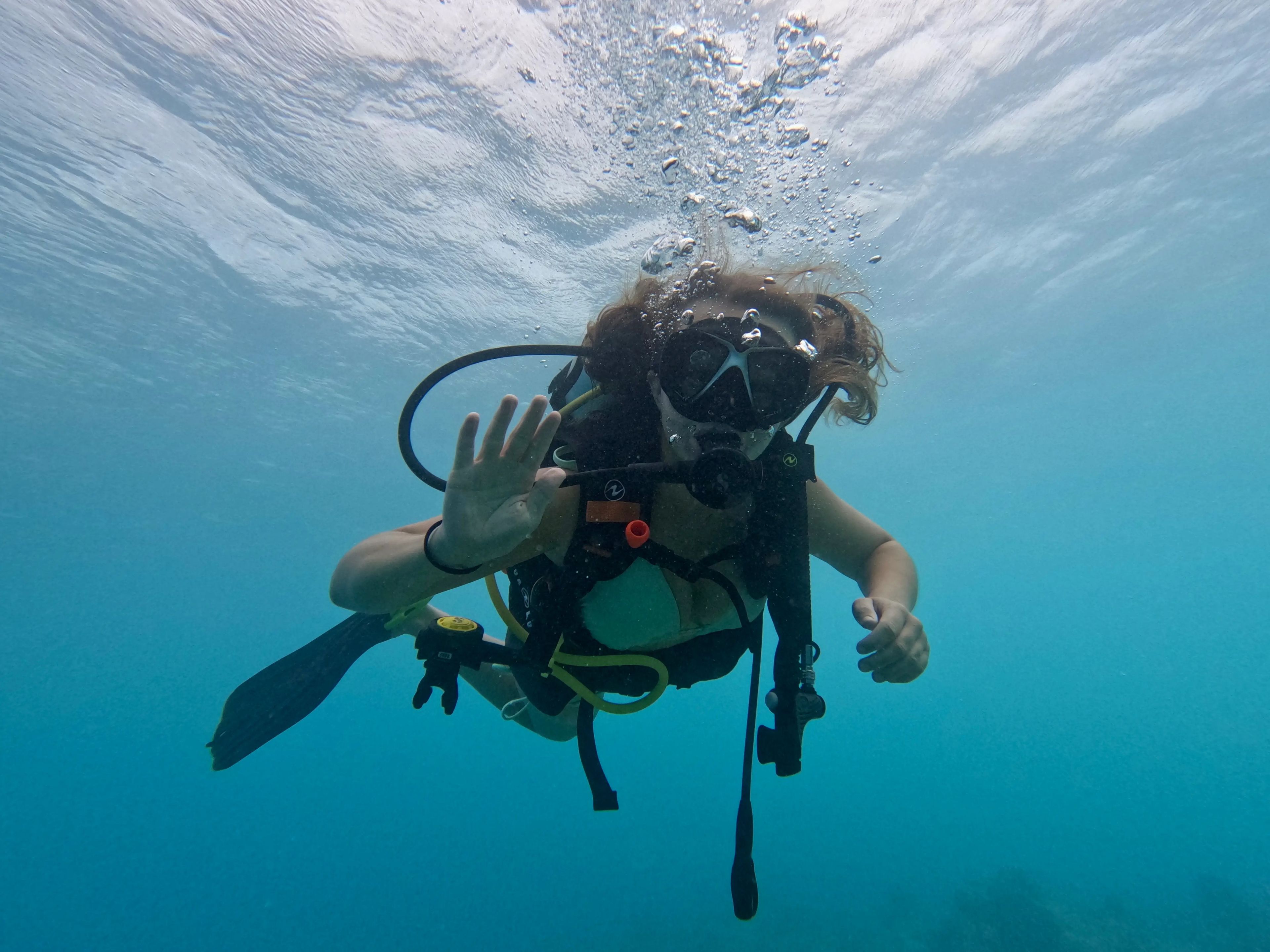 Author Nicole Jordan waving to the camera while snorkeling under water