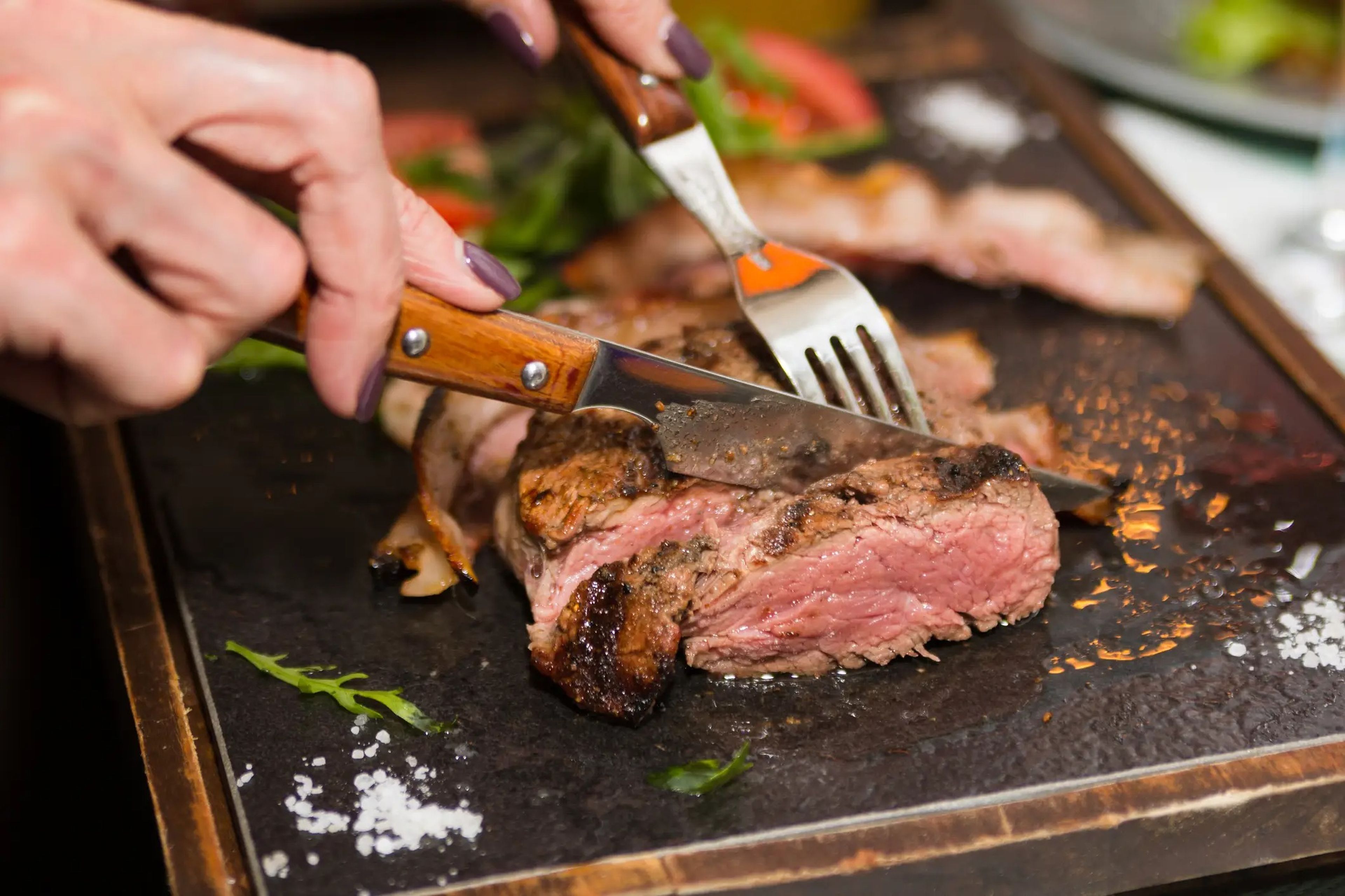 A close up of someone cutting into a juicy steak