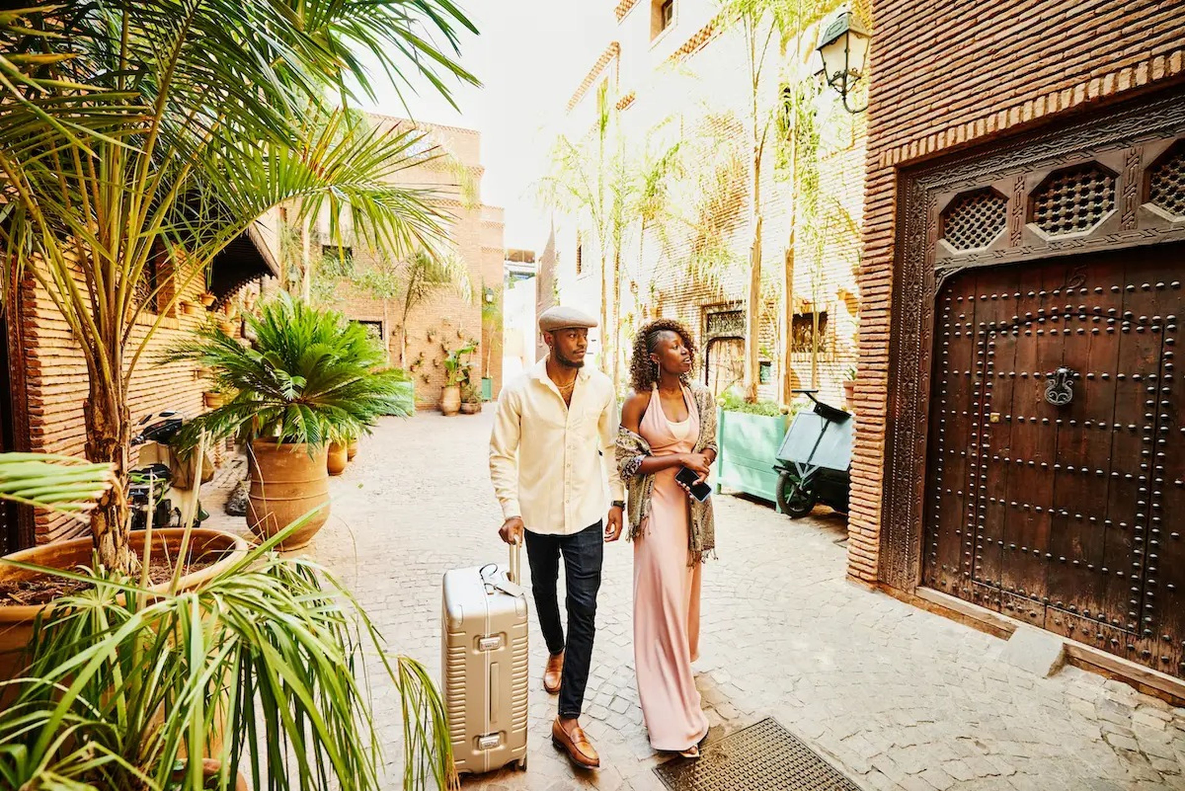 A couple roll a suitcase in a courtyard on vacation.